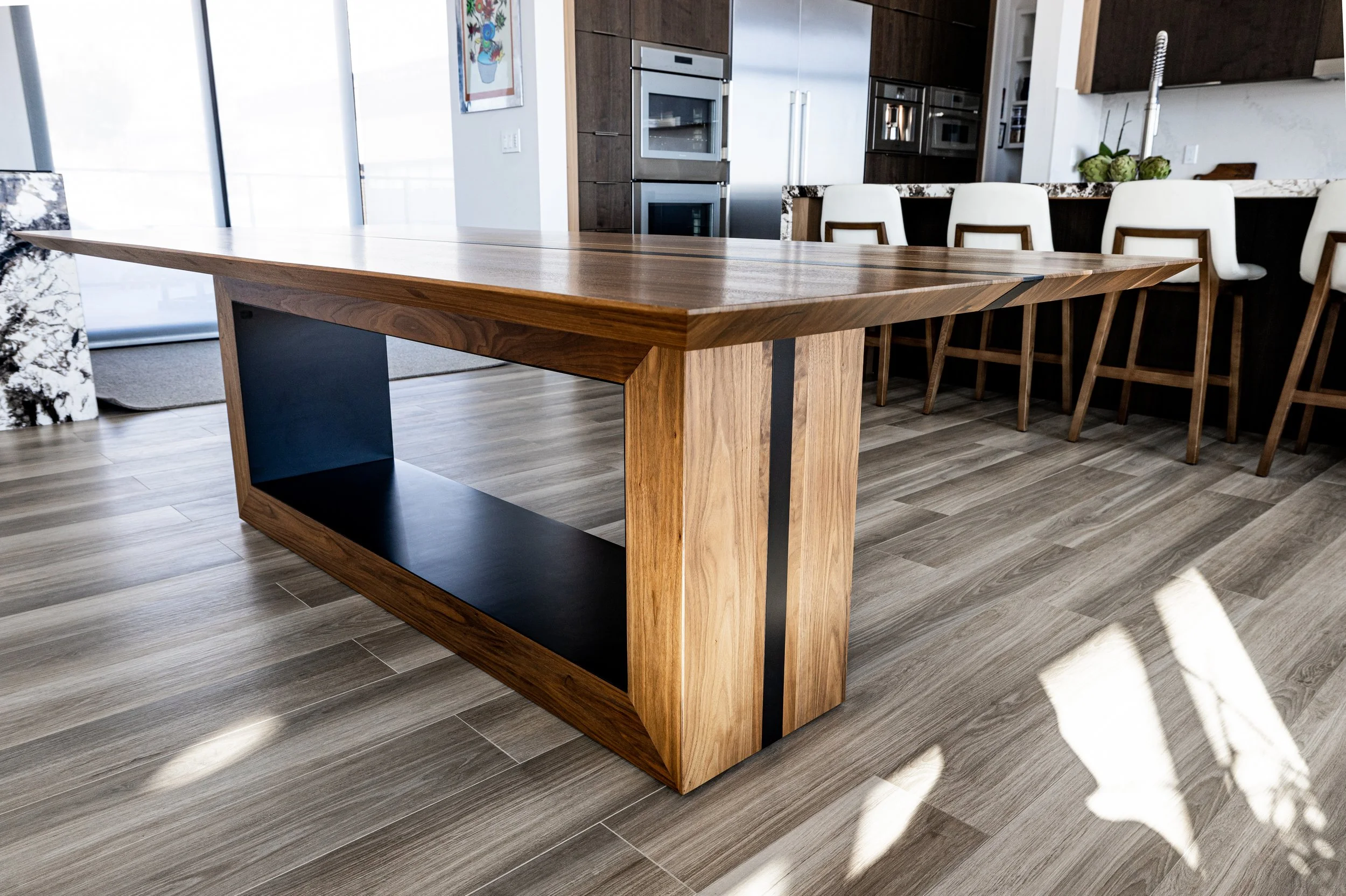 A modern kitchen with a wooden dining table, white chairs, and stainless steel appliances in the background.