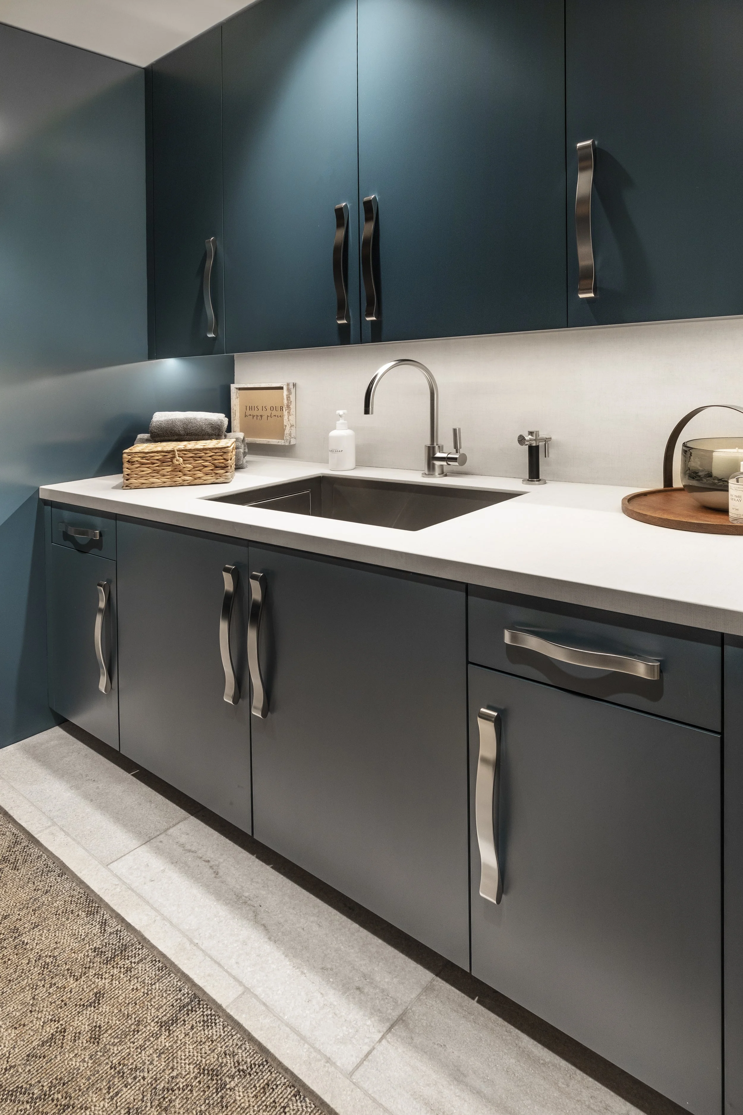 Mountain modern mudroom and laundry room with stone floor and porcelain countertop and backsplash in Martis Camp Truckee CA. Custom bench and lockers painted in a cozy deep blue.