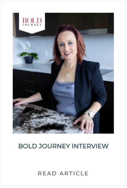 A woman with shoulder-length red hair, wearing a black blazer and light blue top, sits at a kitchen counter with a white orchid plant in the background. The image appears to be a promotional poster for a Bold Journey interview with a "Read Article" call to action.