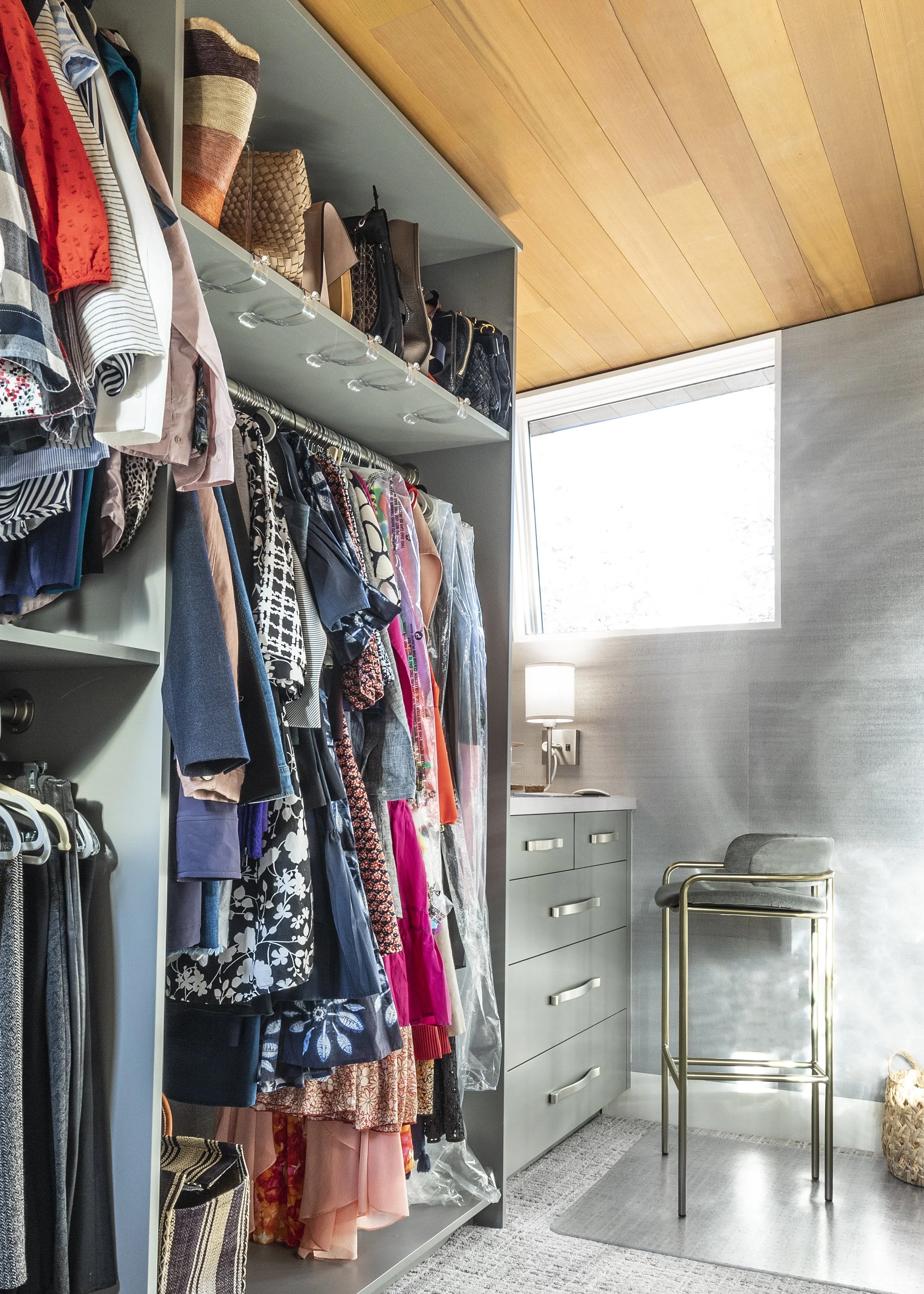 Custom closet for her complete with wallpaper on the walls, wall sconces, a decorative mirror and ample organized storage.