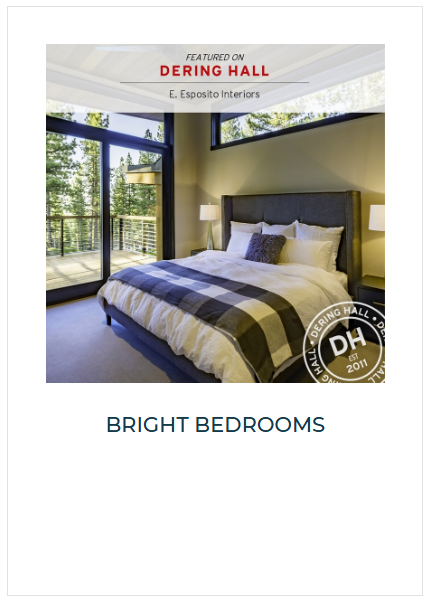 A bedroom with a large bed, white and black striped bedding, and pillows. Two lamps flank the bed. There is a sliding glass door leading to a balcony with trees outside.