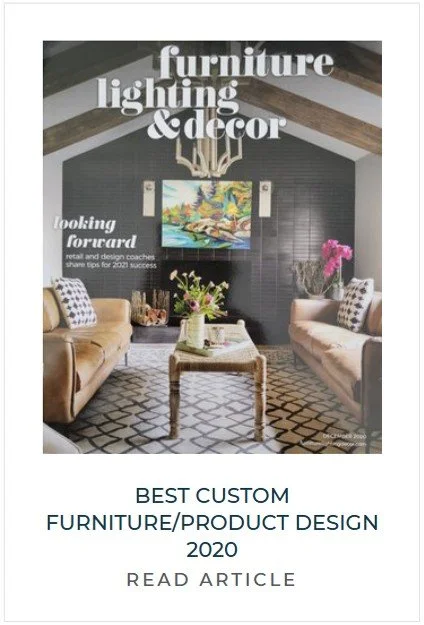 Living room with dark accent wall, two beige sofas with patterned pillows, a coffee table with a vase of flowers, a colorful landscape painting, and a chandelier hanging from a wooden-beamed ceiling.