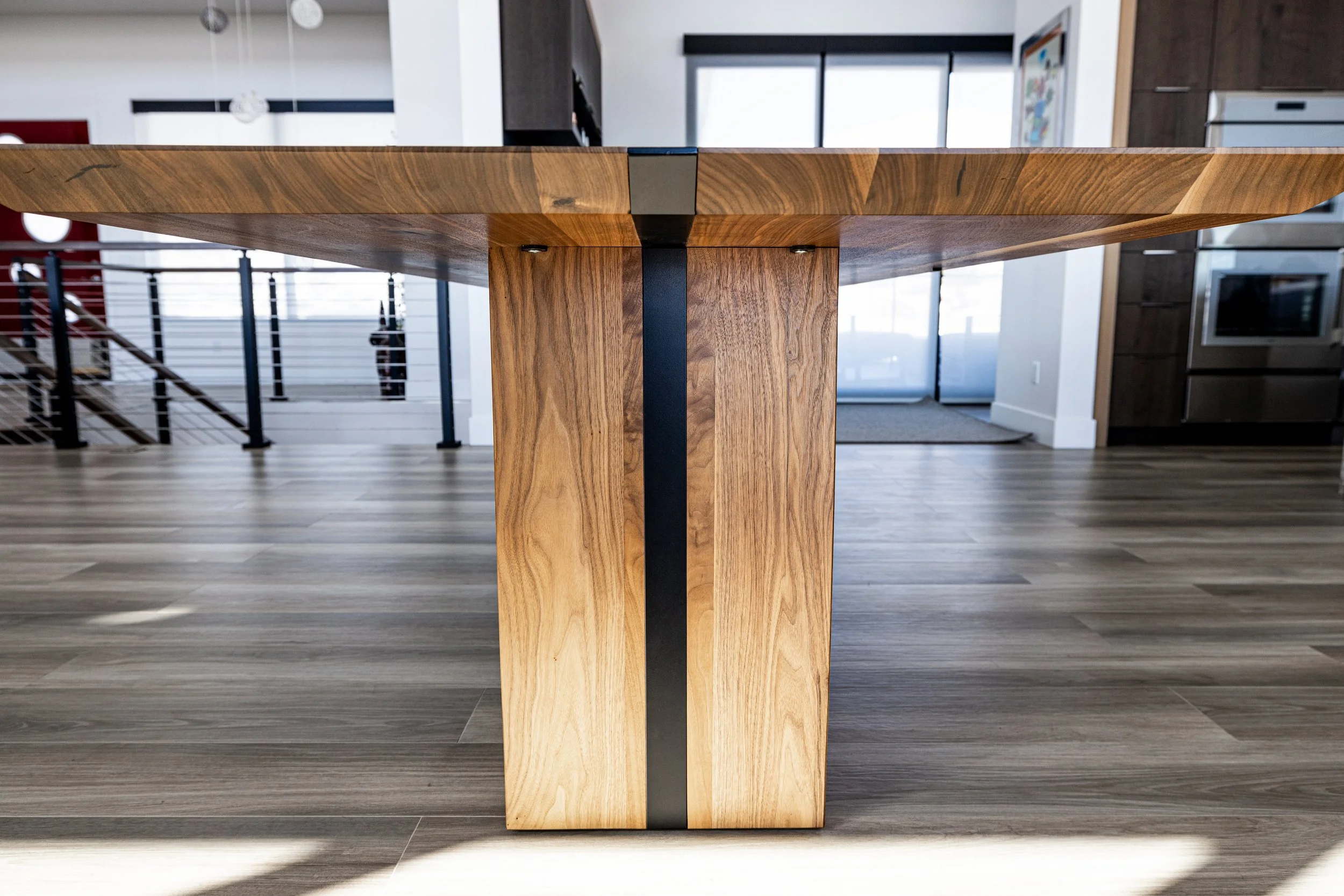 Close-up of a wooden table leg with black metal accents in a modern kitchen or dining area.