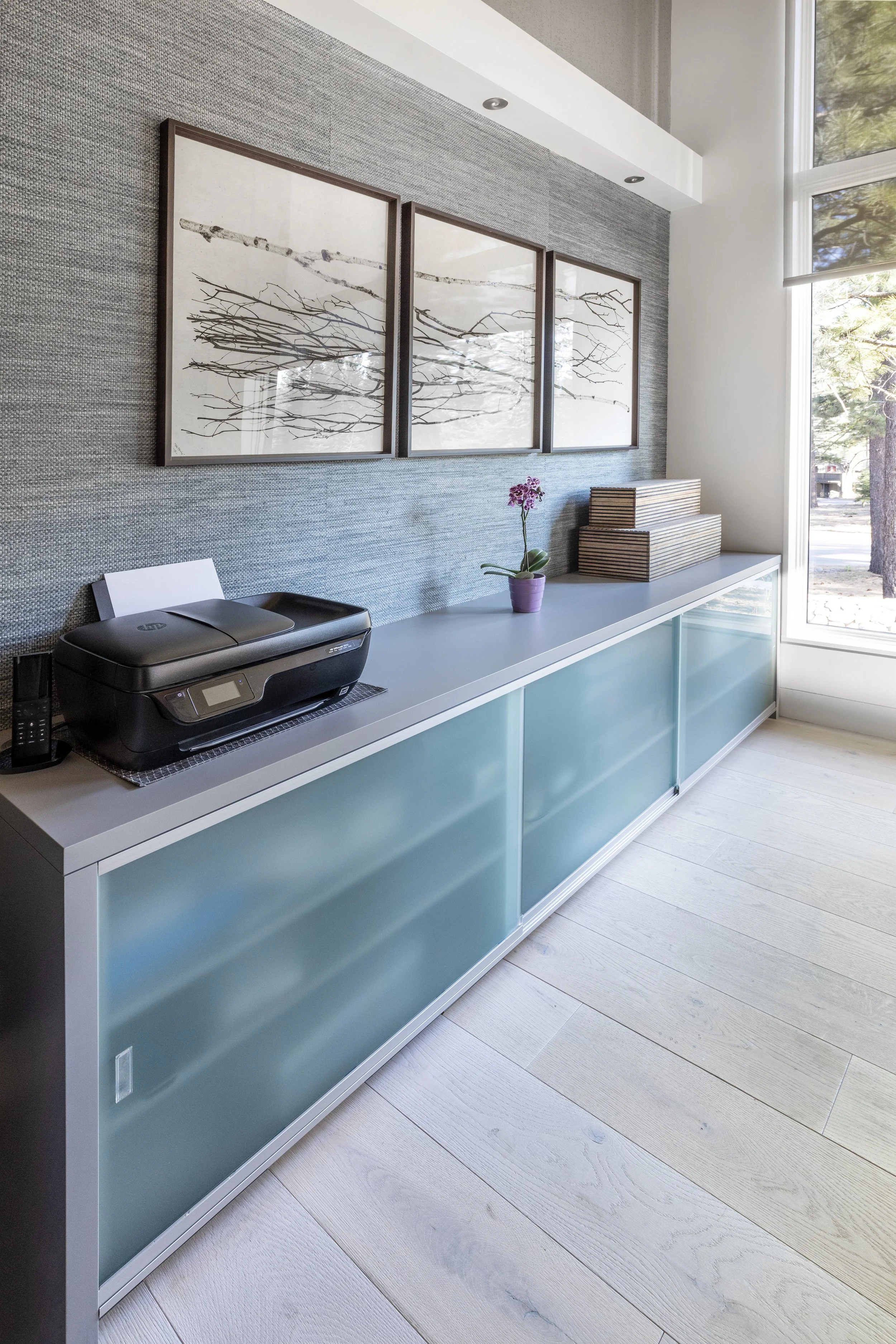 Mountain modern bright media and family room with a custom 4 person desk, a custom storage cabinet with frosted glass sliding doors and walls covered in two textured and natural wallpapers in Martis Camp in Truckee, CA.