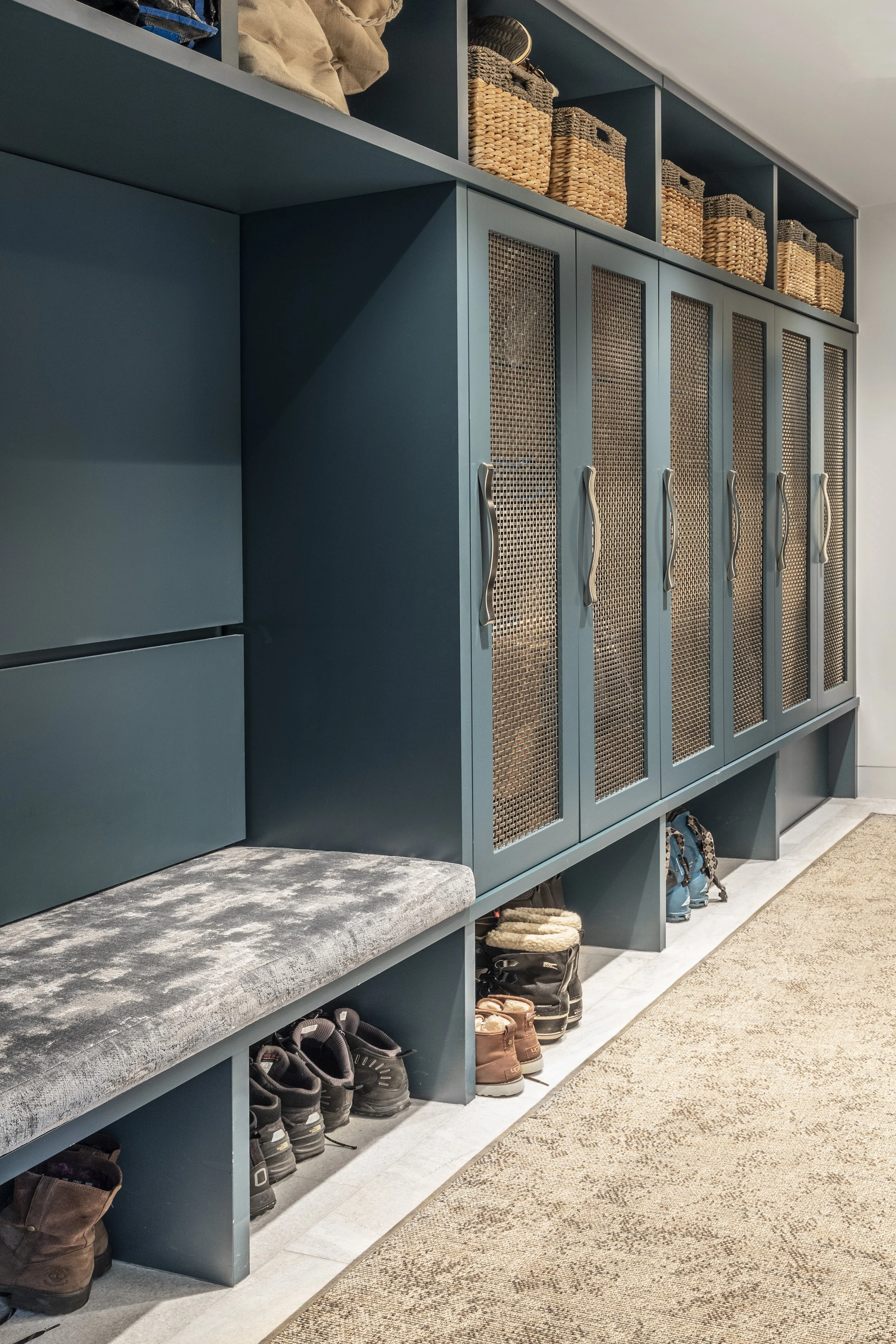 Mountain modern mudroom and laundry room with stone floor and porcelain countertop and backsplash in Martis Camp Truckee CA. Custom bench and lockers painted in a cozy deep blue.