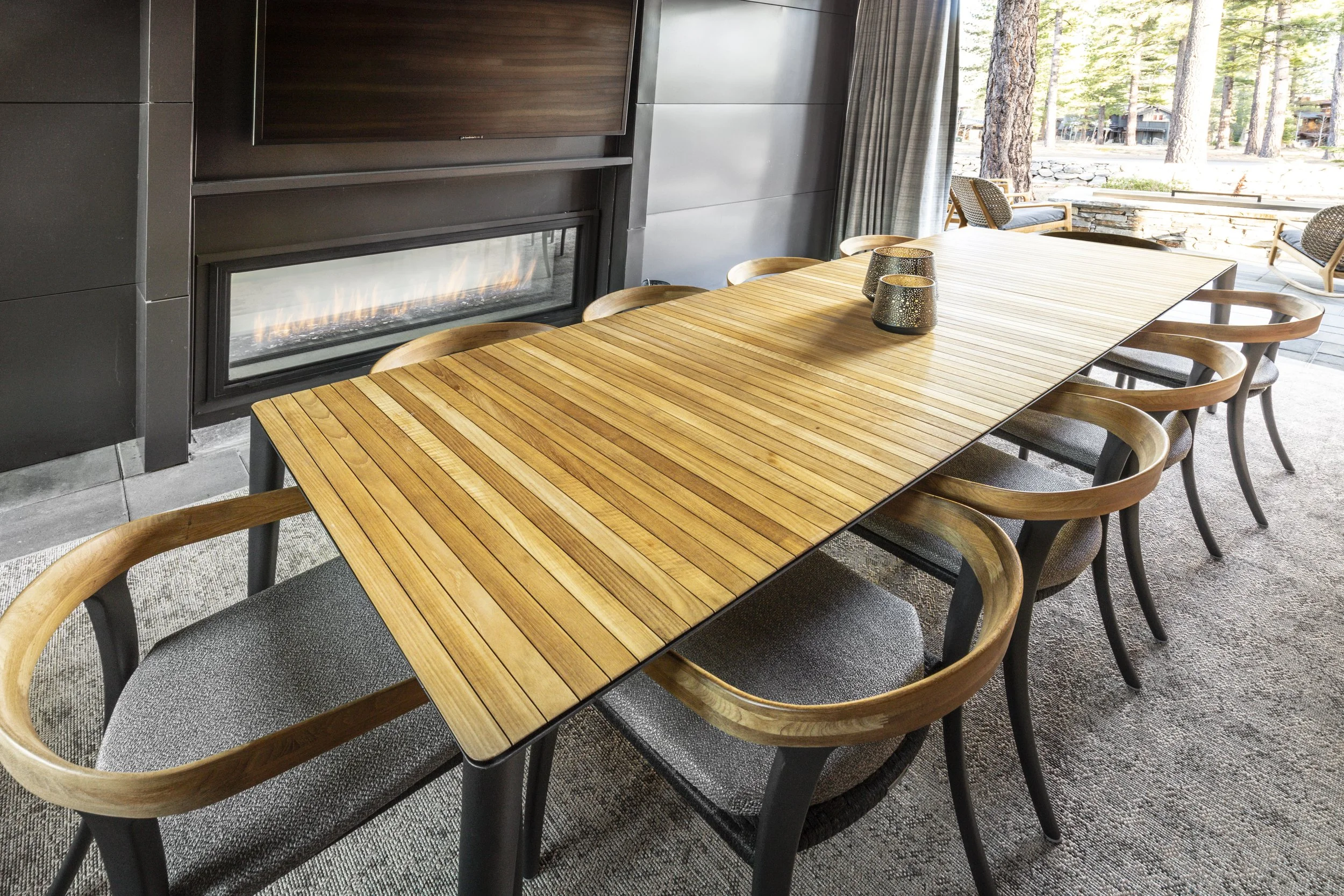 Mountain modern outdoor dining room with 2 way fireplace, heaters in the ceiling for year-round use, and decorative outdoor draperies to keep the space cozy and warm during the colder months in Martis Camp in Truckee, CA.