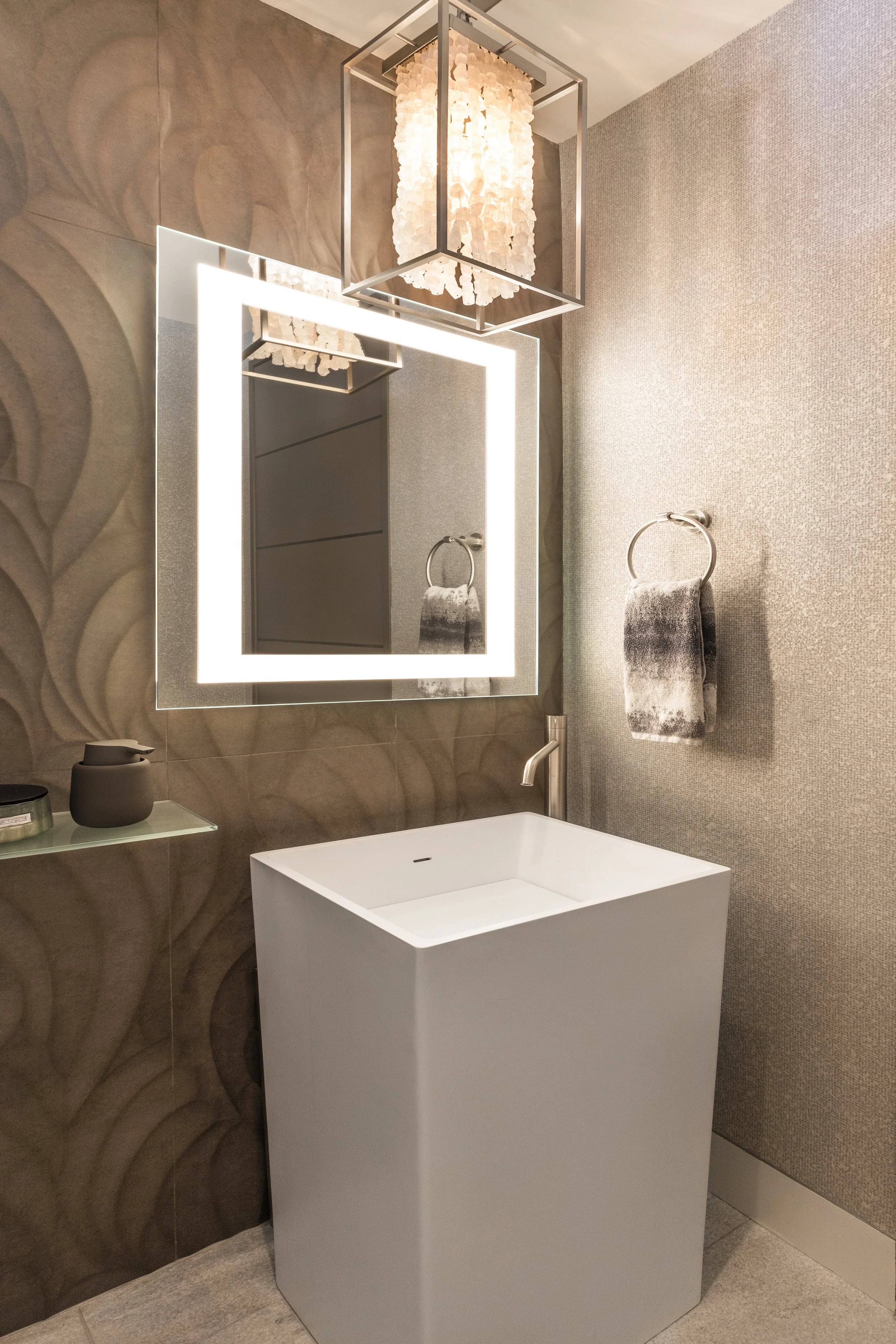Mountain modern powder room with dimensional porcelain cladded wall behind the freestanding sink and all other walls dressed in natural shimmery mica wallpaper in Martis Camp Truckee CA. Rock crystal pendant floats over the freestanding sink and floo