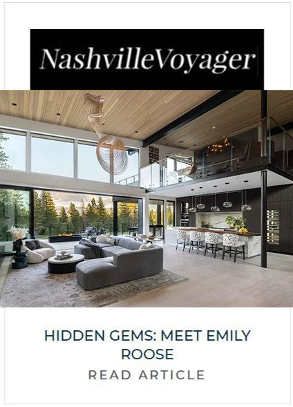 Modern living room with large windows, overstuffed sofas, and a view of greenery outside. Open kitchen with island and bar stools, two levels with a balcony, and a wooden ceiling.