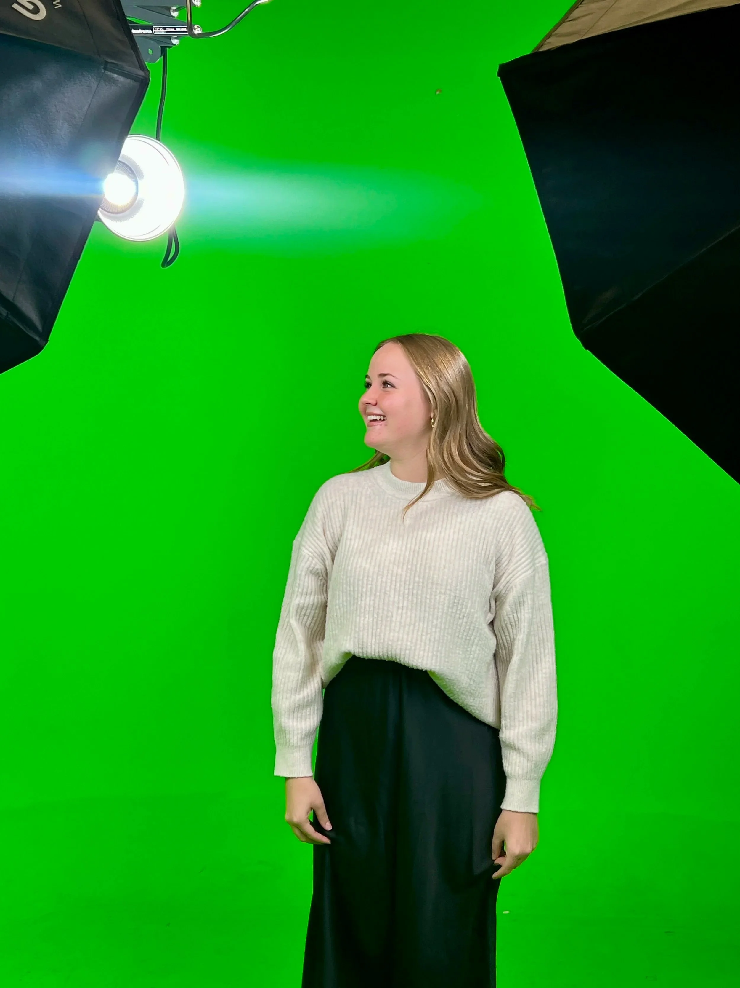 Kayla filming green screen work, laughing and smiling.