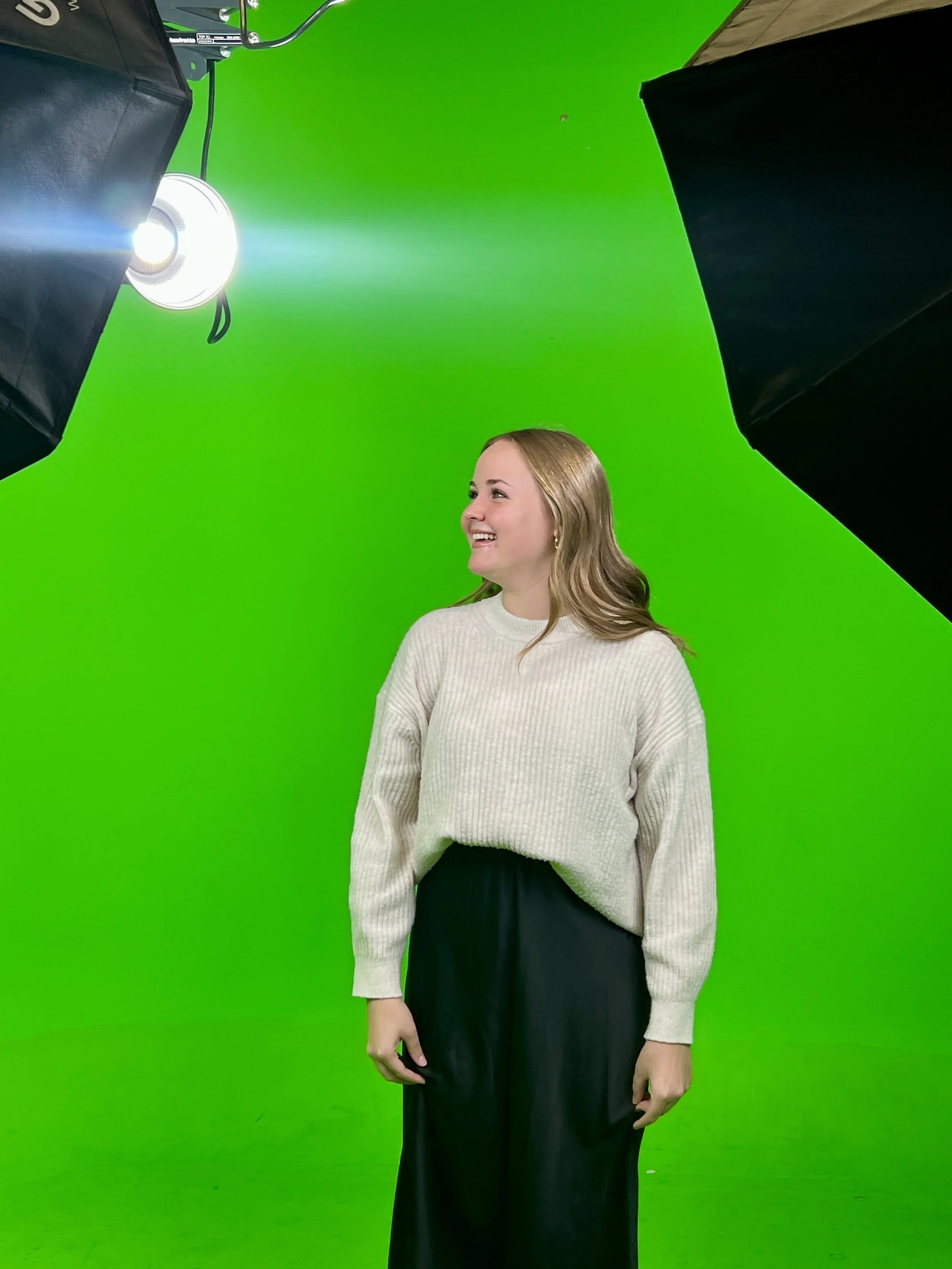 Kayla filming green screen work, laughing and smiling.
