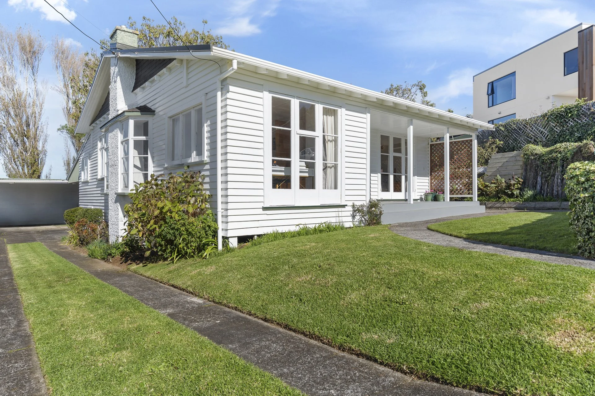 3 Barrett Street, Westown, New Plymouth.  A character family house with a lawn and garden, large windows, and a small porch area. The house is situated in a suburban neighborhood with other modern buildings nearby.