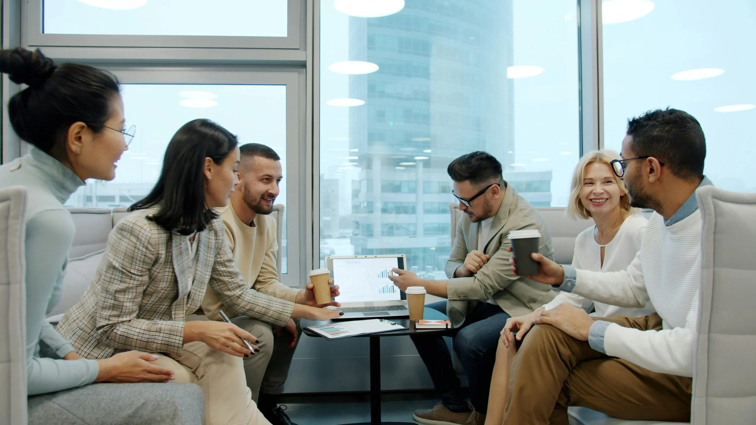 A group of colleagues are sitting together with a computer at the center. They are preparing a meeting