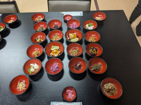 A table with about twenty different bowls that all contain different kind of temple food