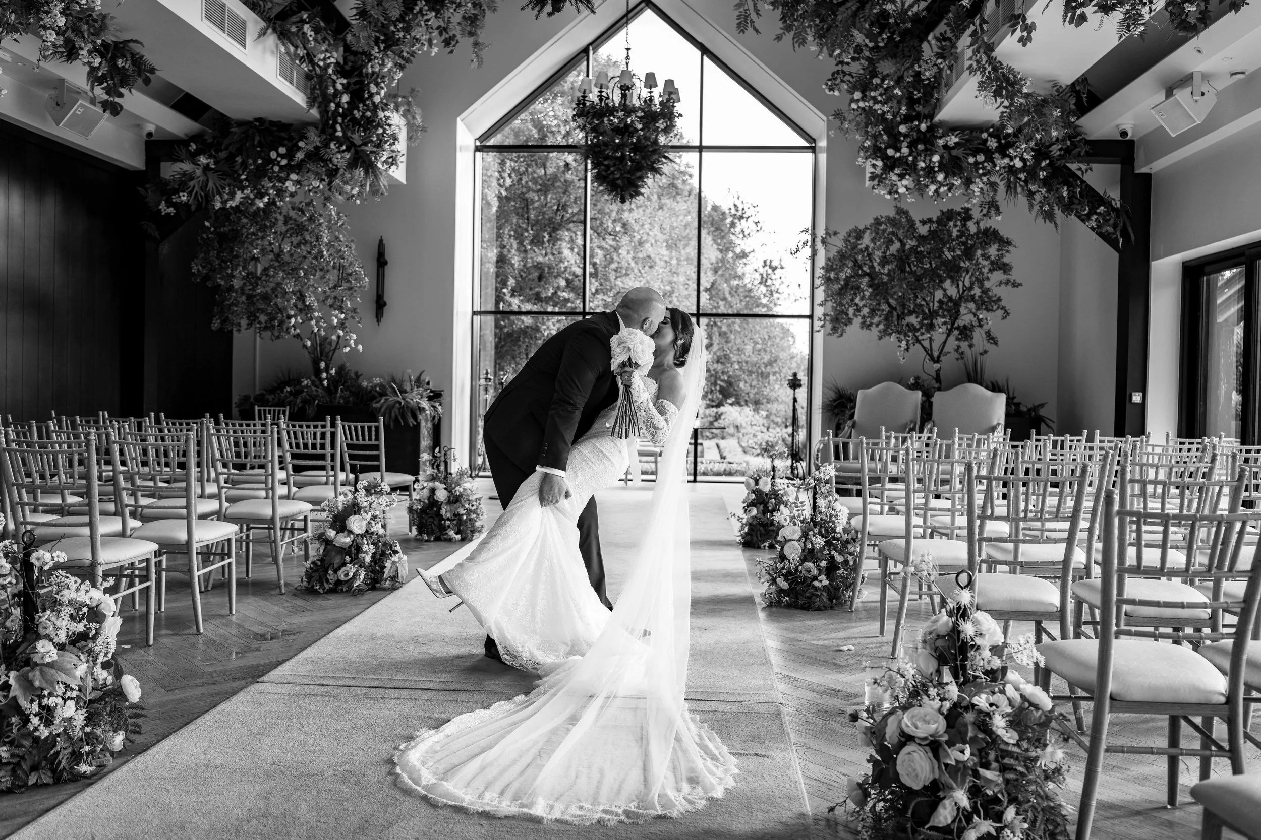 A bride and groom share a kiss in a church decorated with flowers during their wedding.