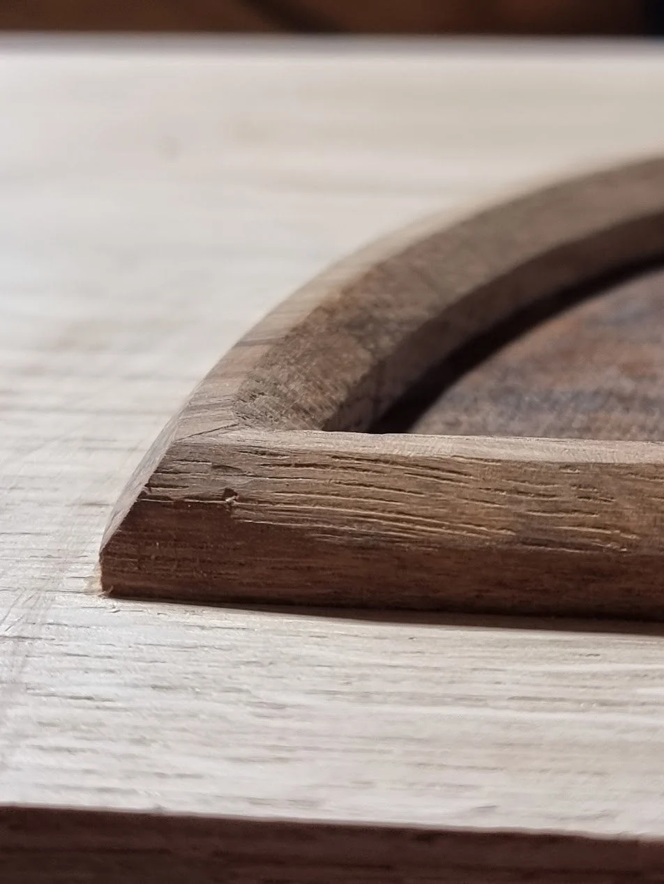 Close-up of a wooden frame or edge on a light-colored wooden surface.
