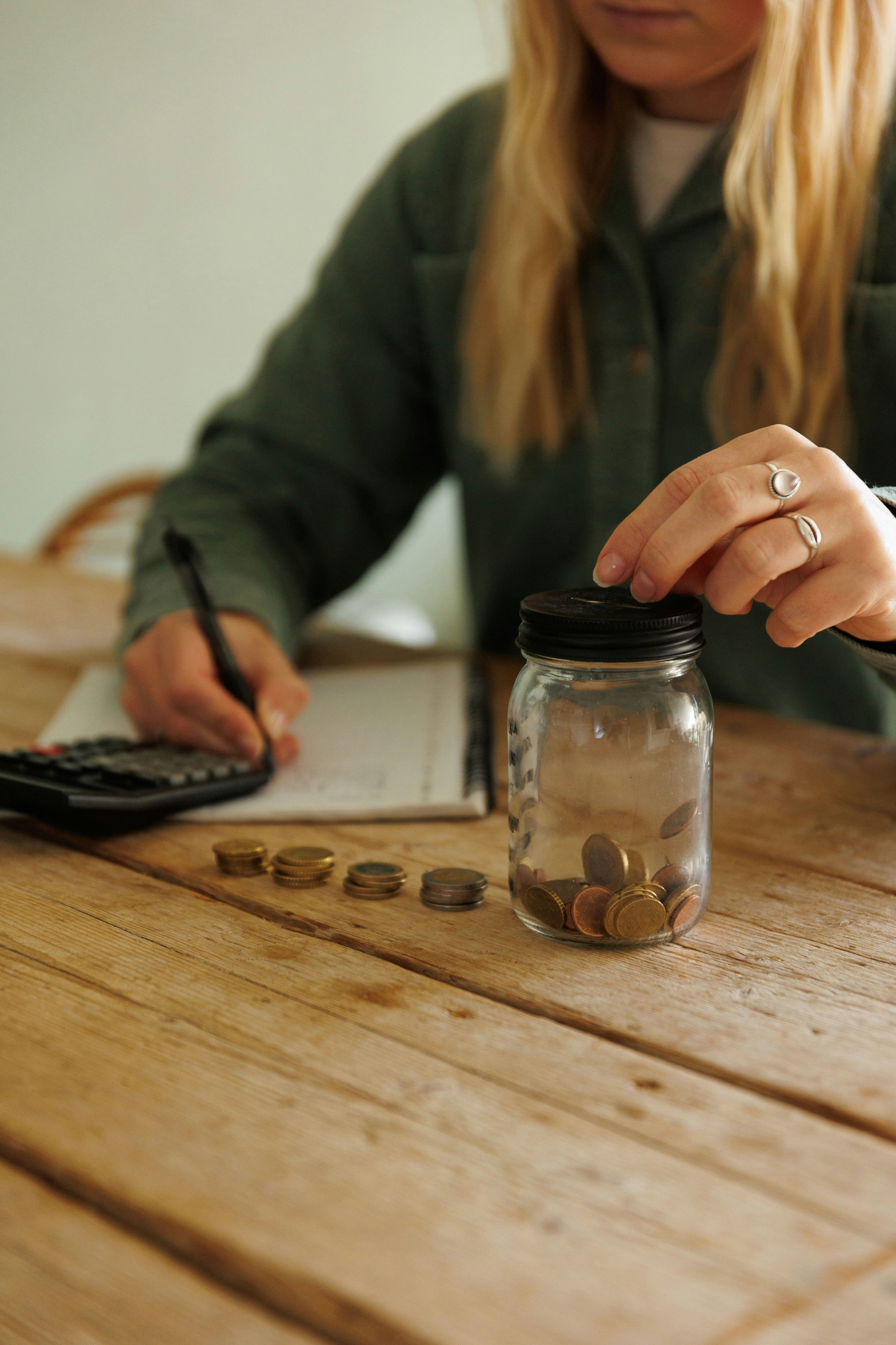 A woman drops money into a jar and notes in on paper