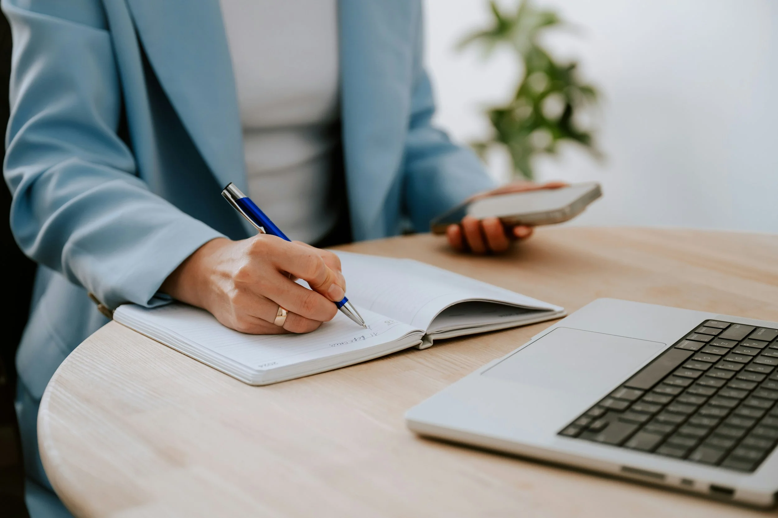 A woman in a blue vest writes in a notebook