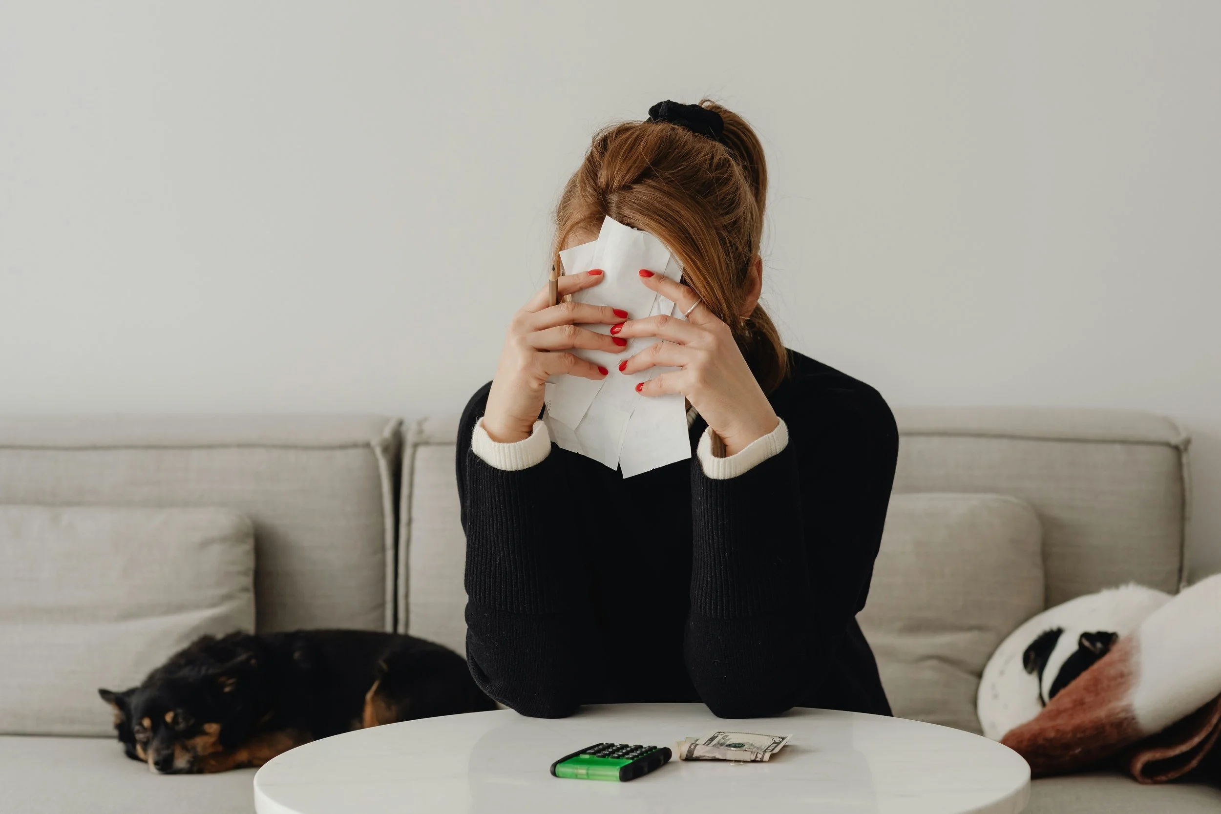 A woman holds receipts to her face, stressed