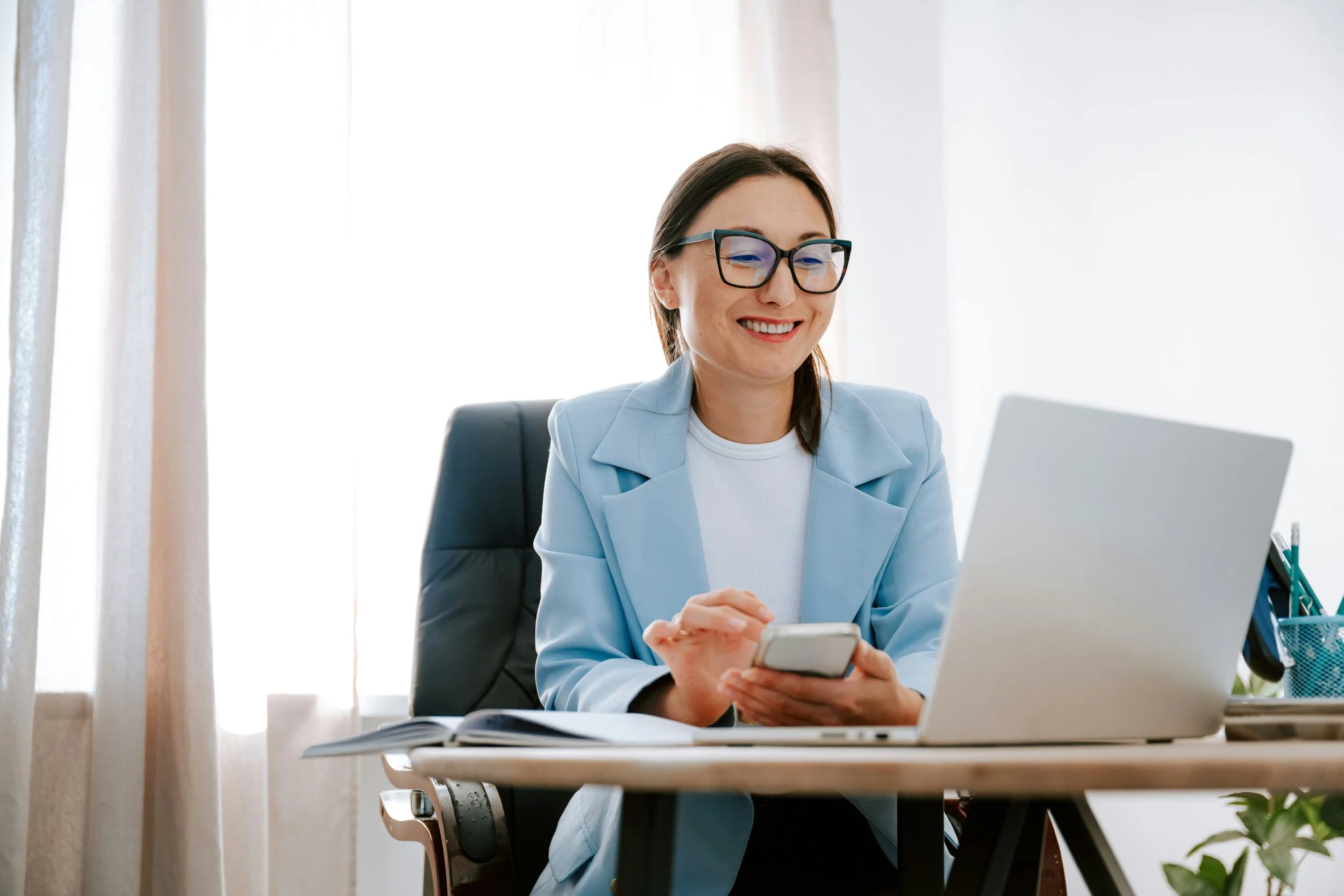 A woman sits at a desk in a blue blazer