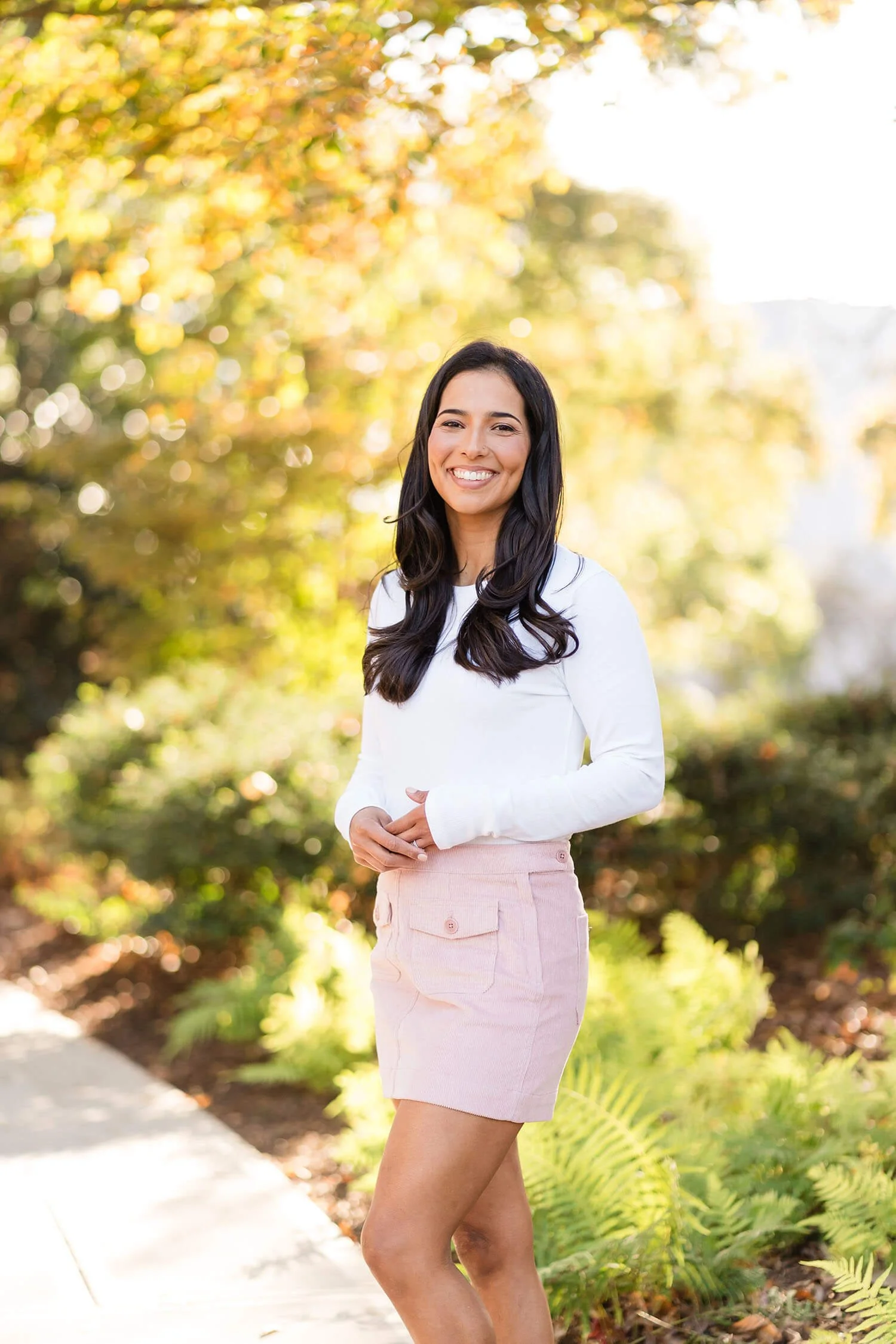 Lenet smiles outside in a white shirt and pink skirt