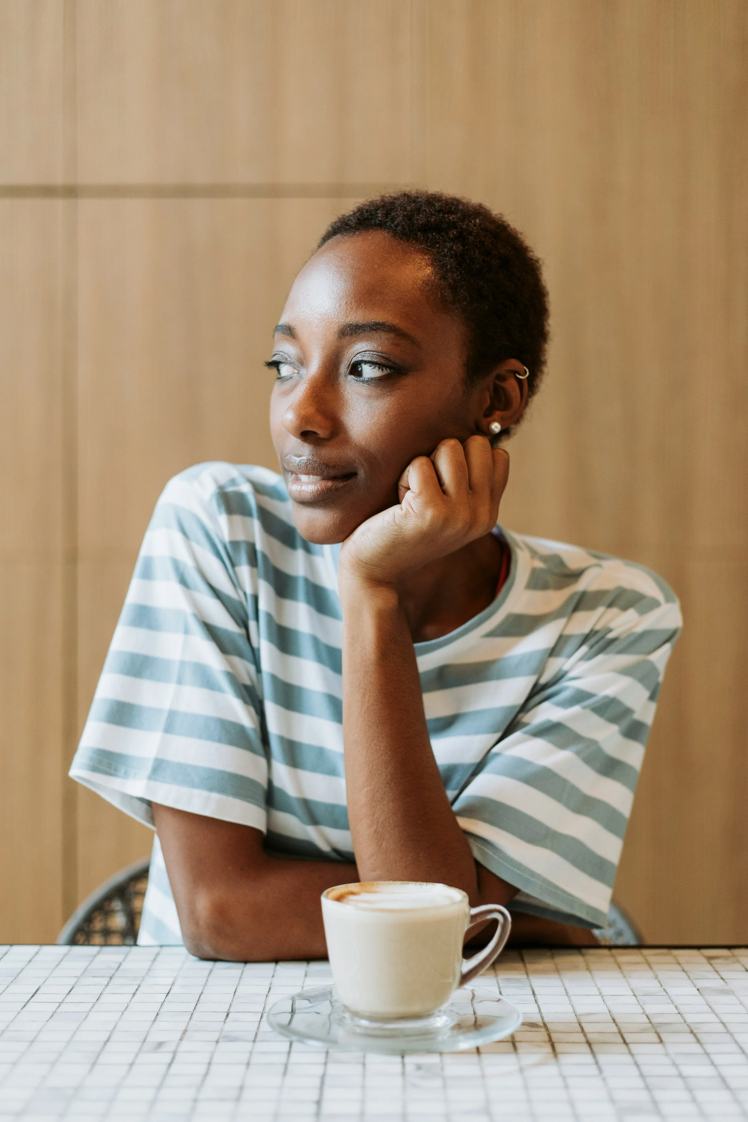 A woman in a striped shirt rests her chin on her hand