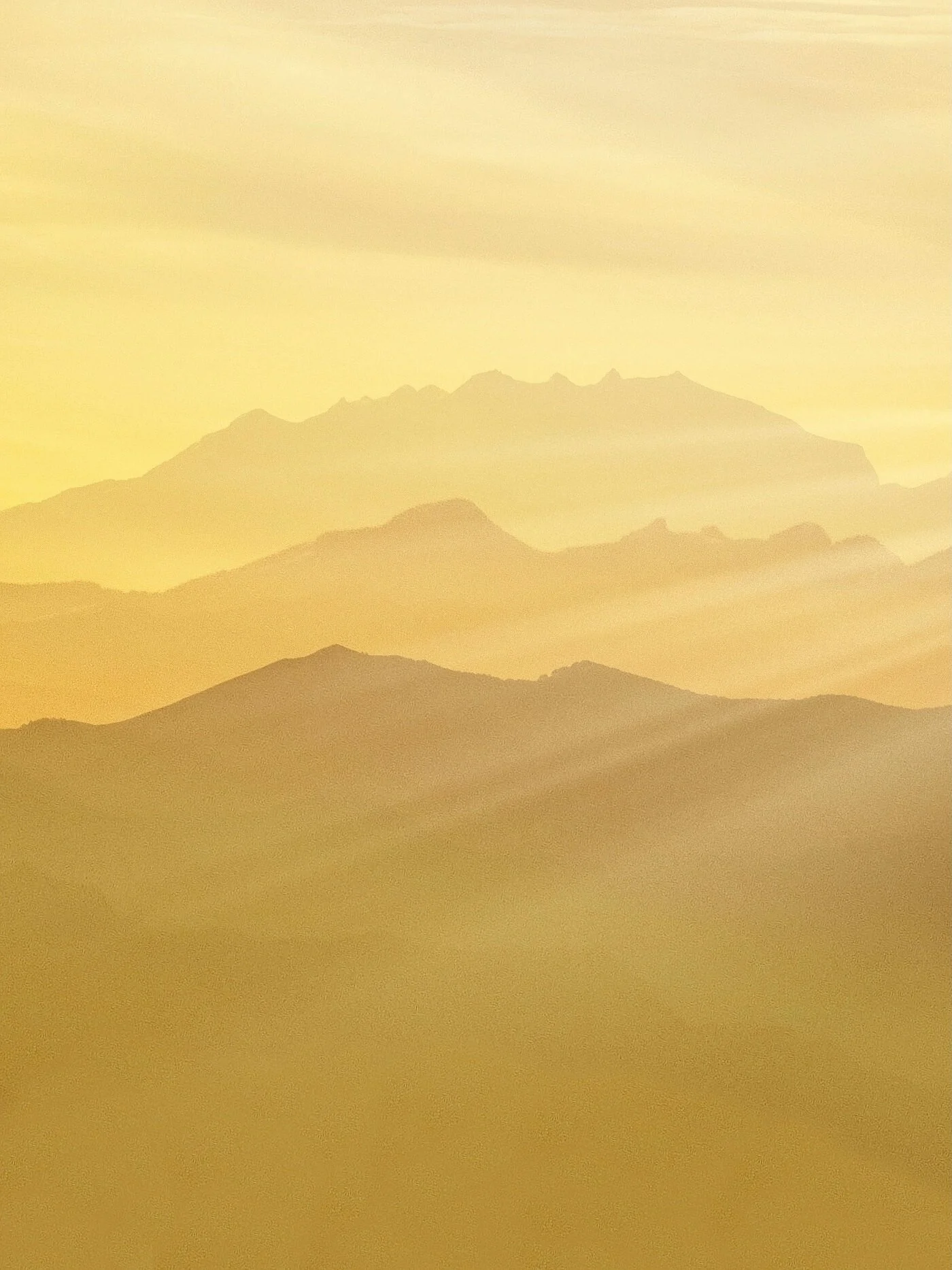 Silhouetted mountain range under a yellow-orange sky with some clouds