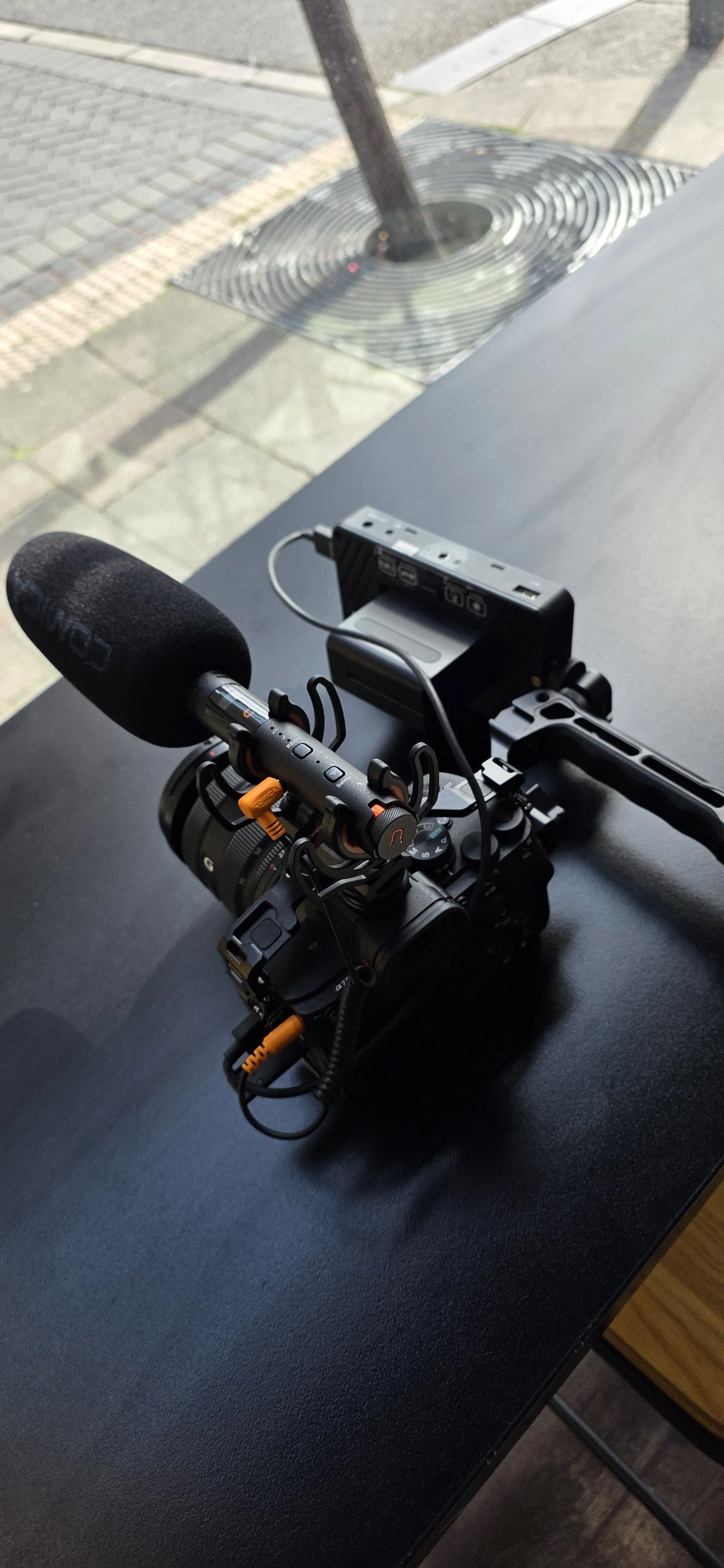 A Sony camera with a 40mm lens and two additional Canon lenses on a dark surface.