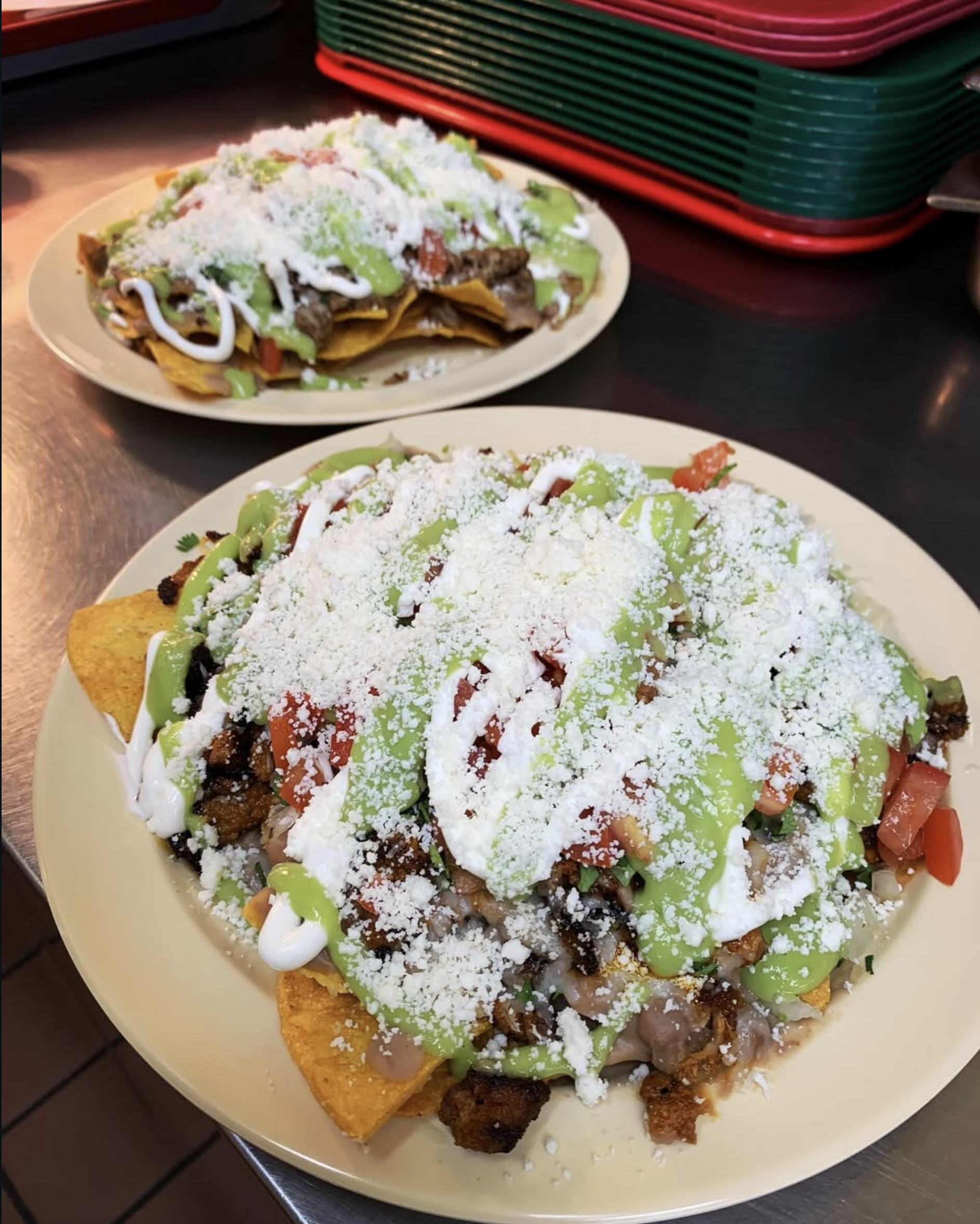 Two plates of loaded nachos topped with flavorful ingredients sure to fill you up.