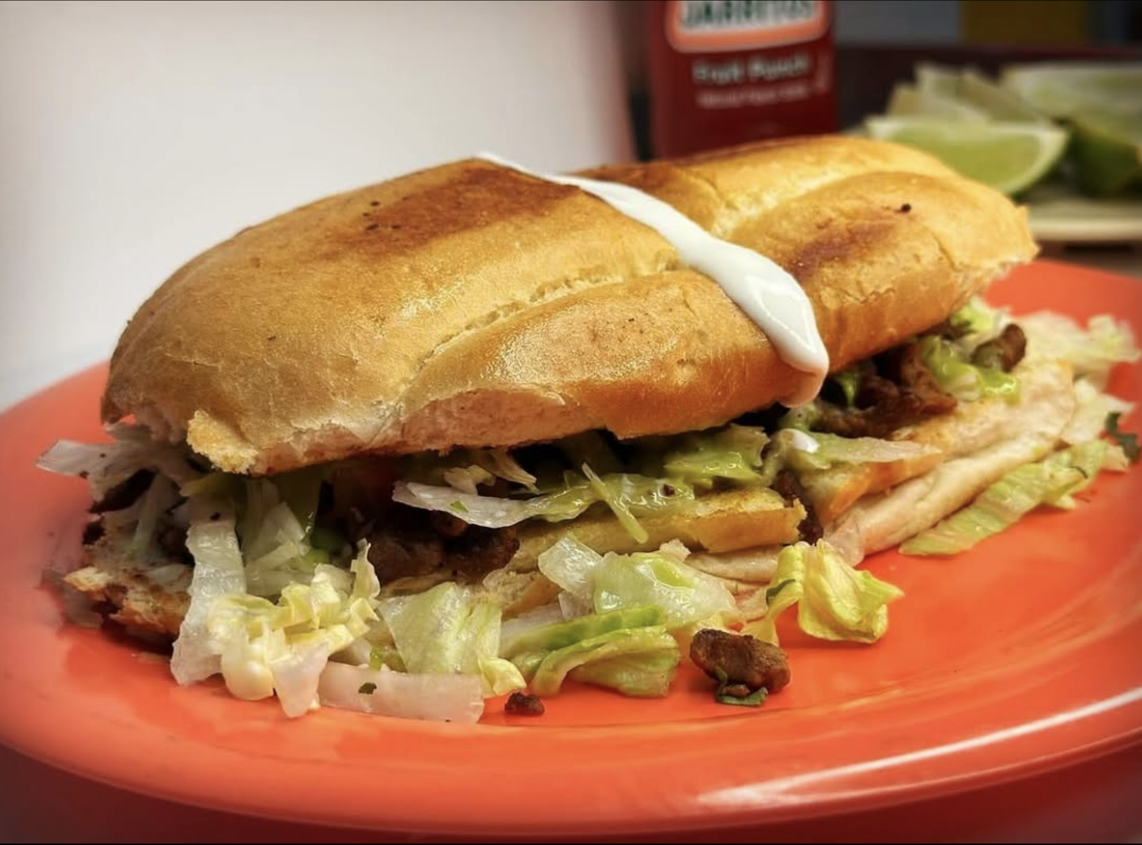 A torta with a toasted bun, shredded lettuce, grilled meat, mayonnaise and more.
