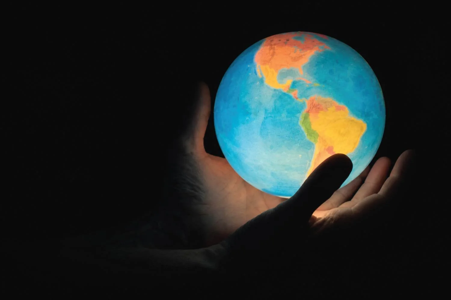 Hands holding a glowing globe