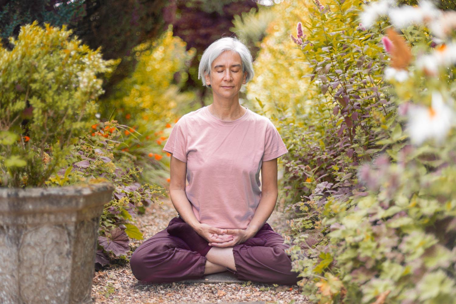 A woman meditating in a garden-like setting