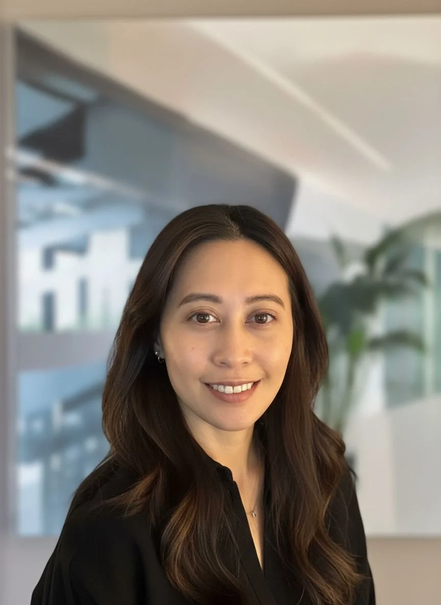 Professional woman with long brown hair smiling in an office setting.