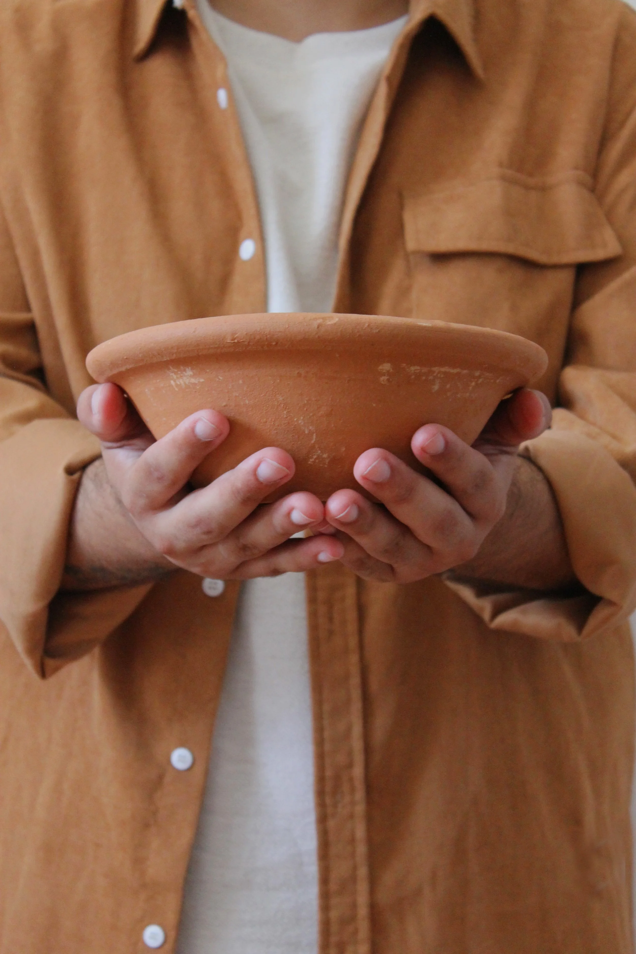Pessoa segurando um prato de barro sem detalhes visíveis