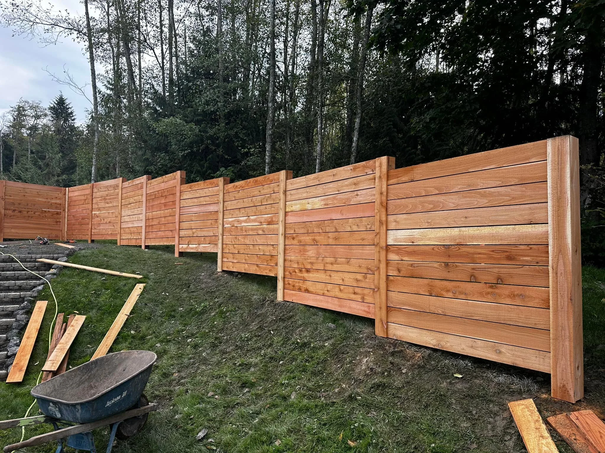 Wooden fence under construction with landscape and trees in the background.