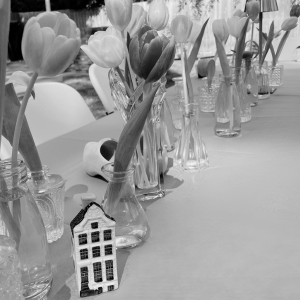 tulip centerpieces in bud vases along a table with a small Dutch house and wooden shoe