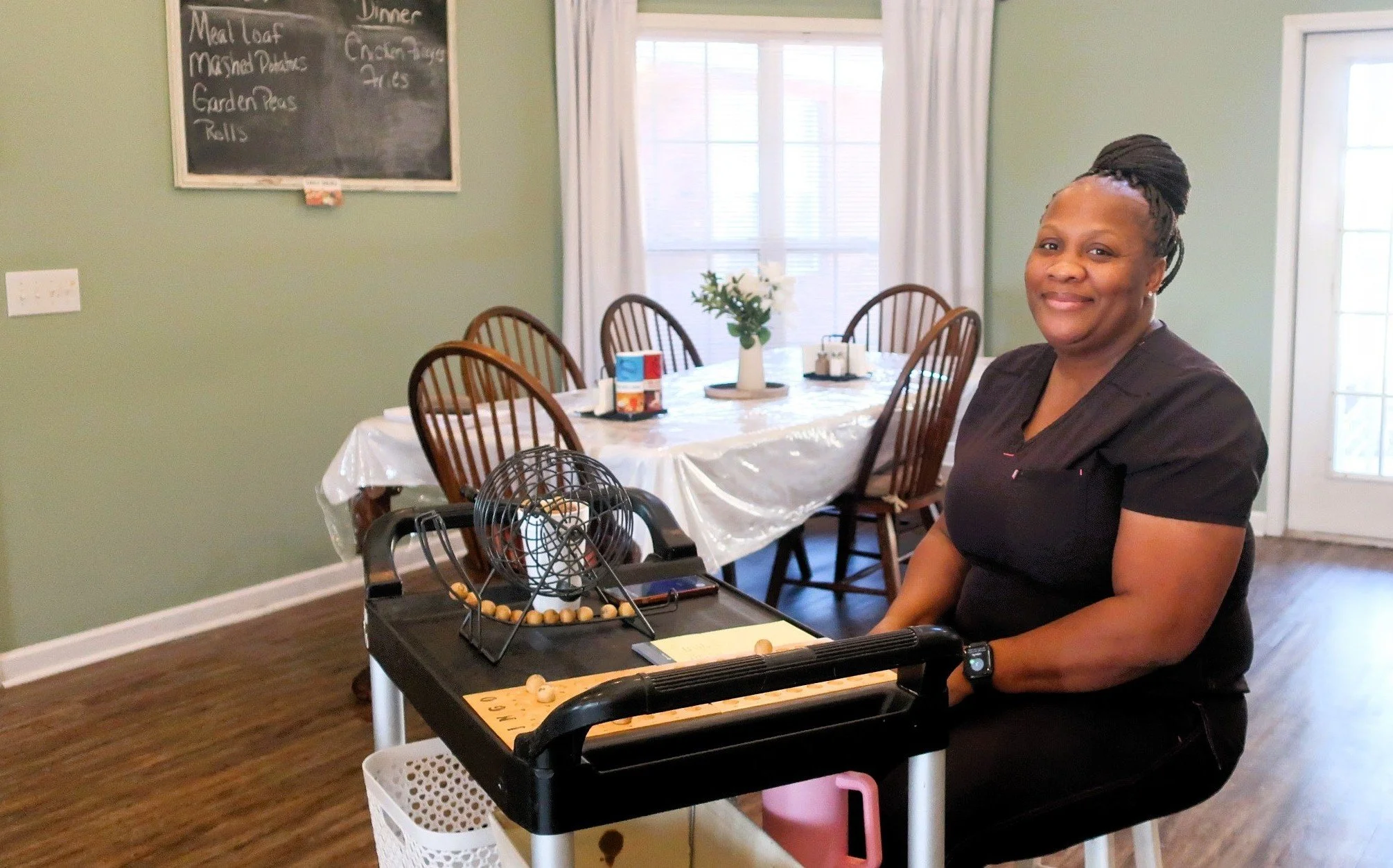 Woman sitting in a dining room with a bingo game on a cart
