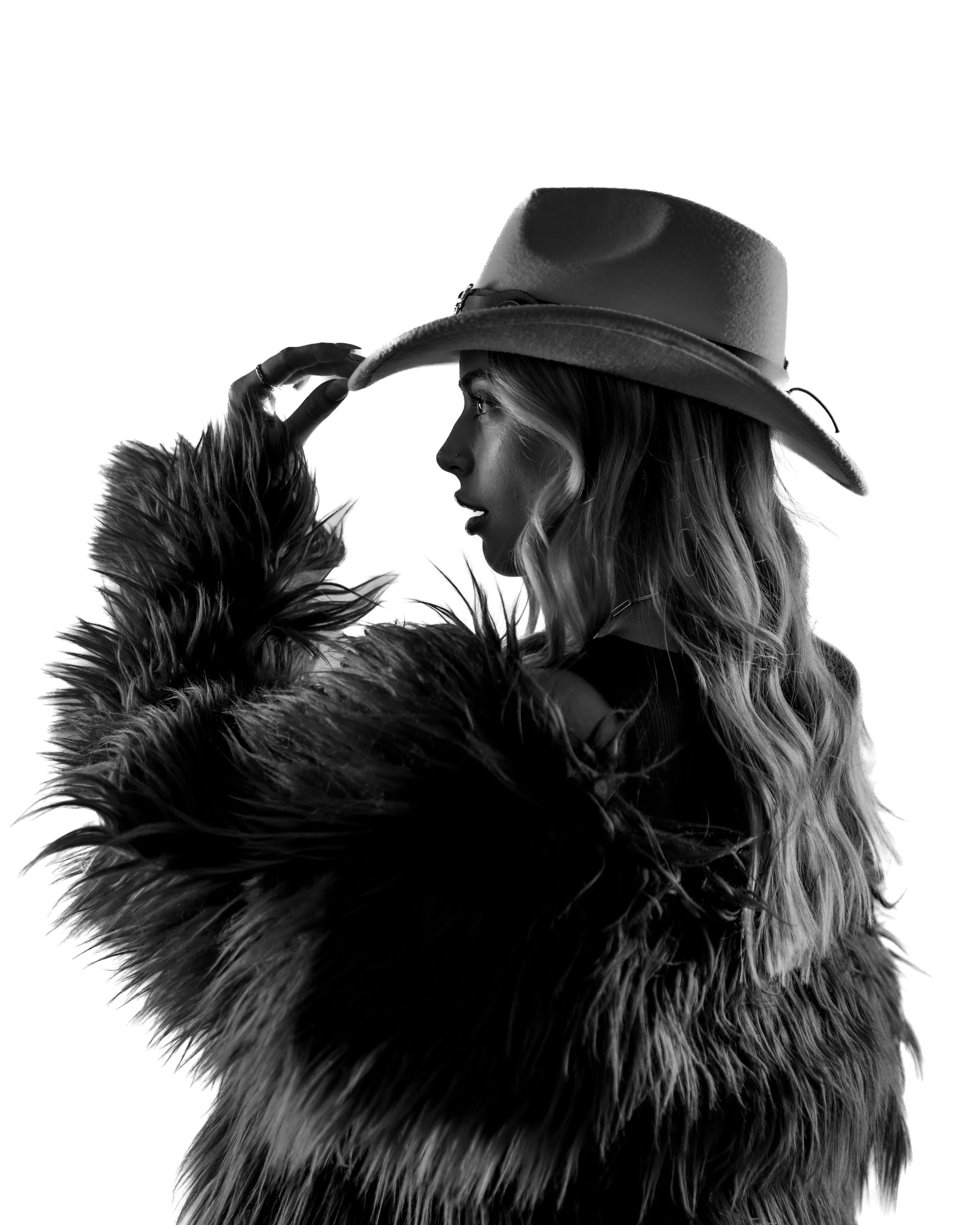 Black and white photo of a girl in fur coat wearing a cowboy hat. Studio portait taken In Austin Texas