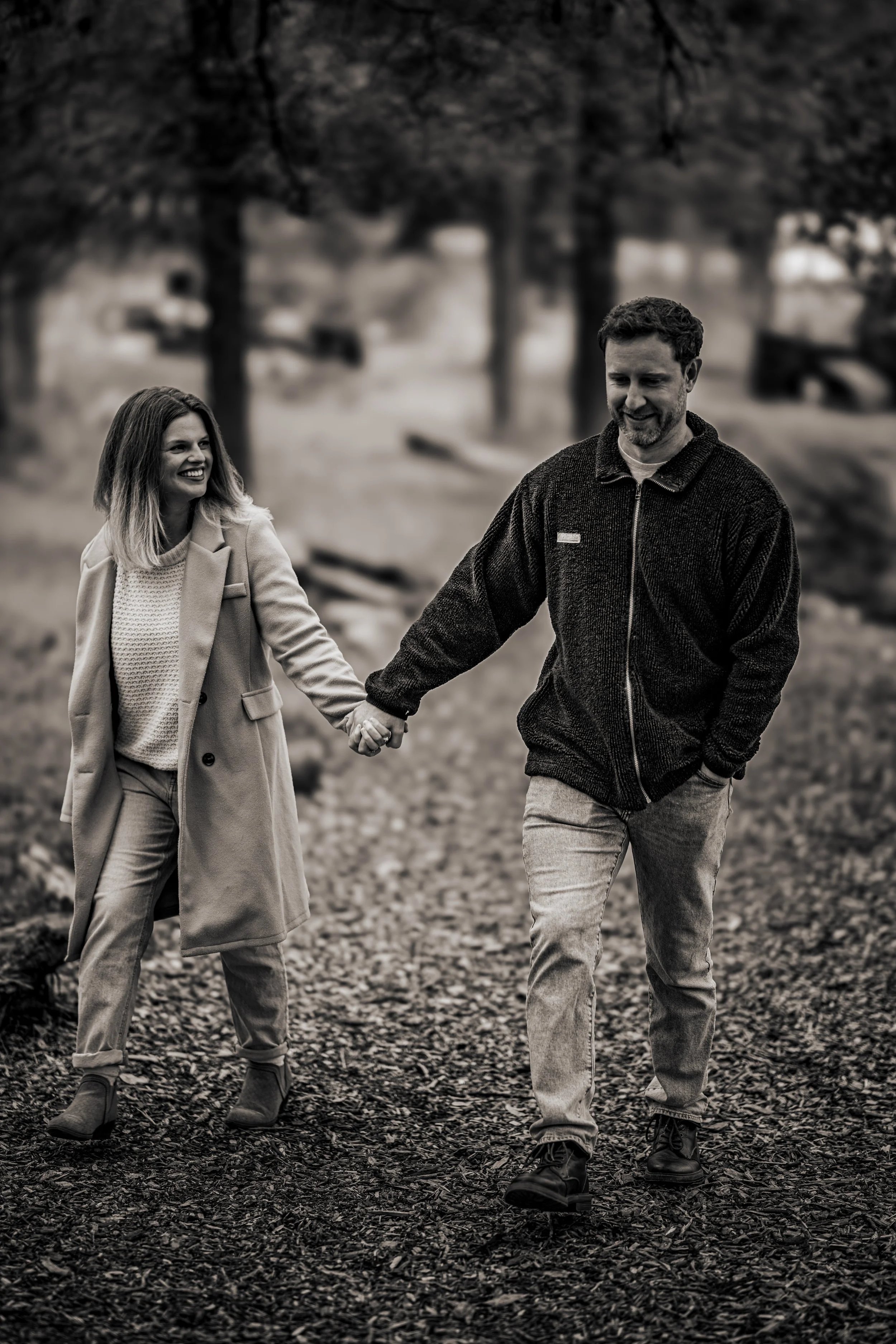A black and white photo of a couple walking and holding hands. Taken at Pease District Park in Austin Texas by Austin Texas photographer