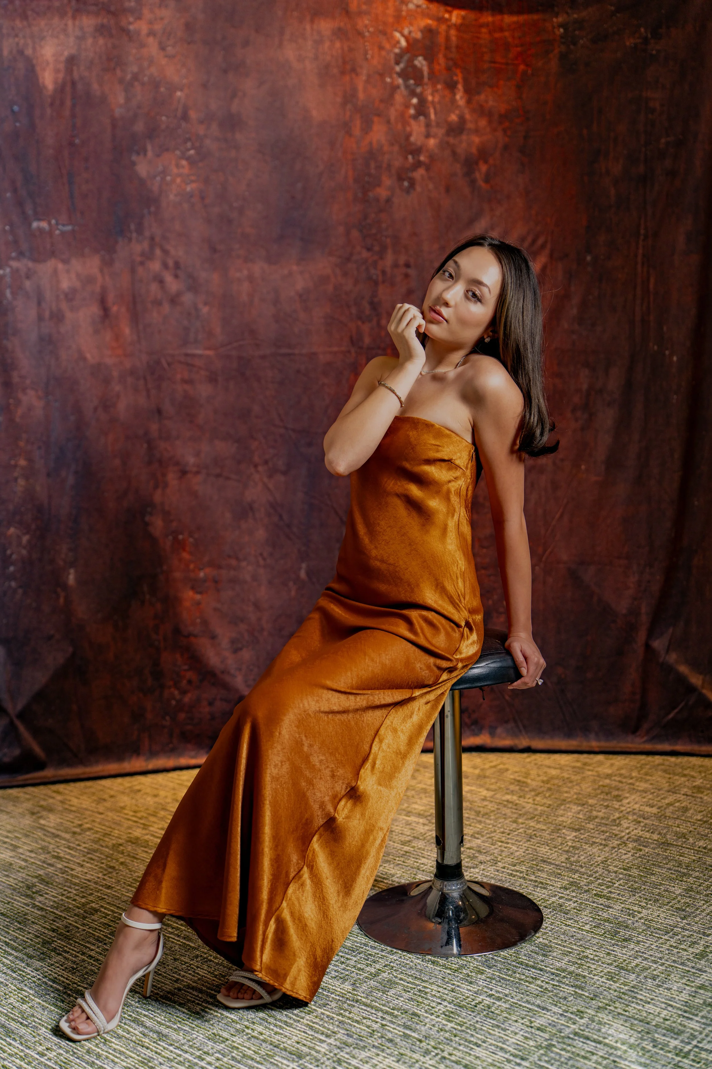 Portrait of a girl in heels and floor length dress sitting on a stool. Portrait taken by an Austin Texas photgapher in Austin Texas. 