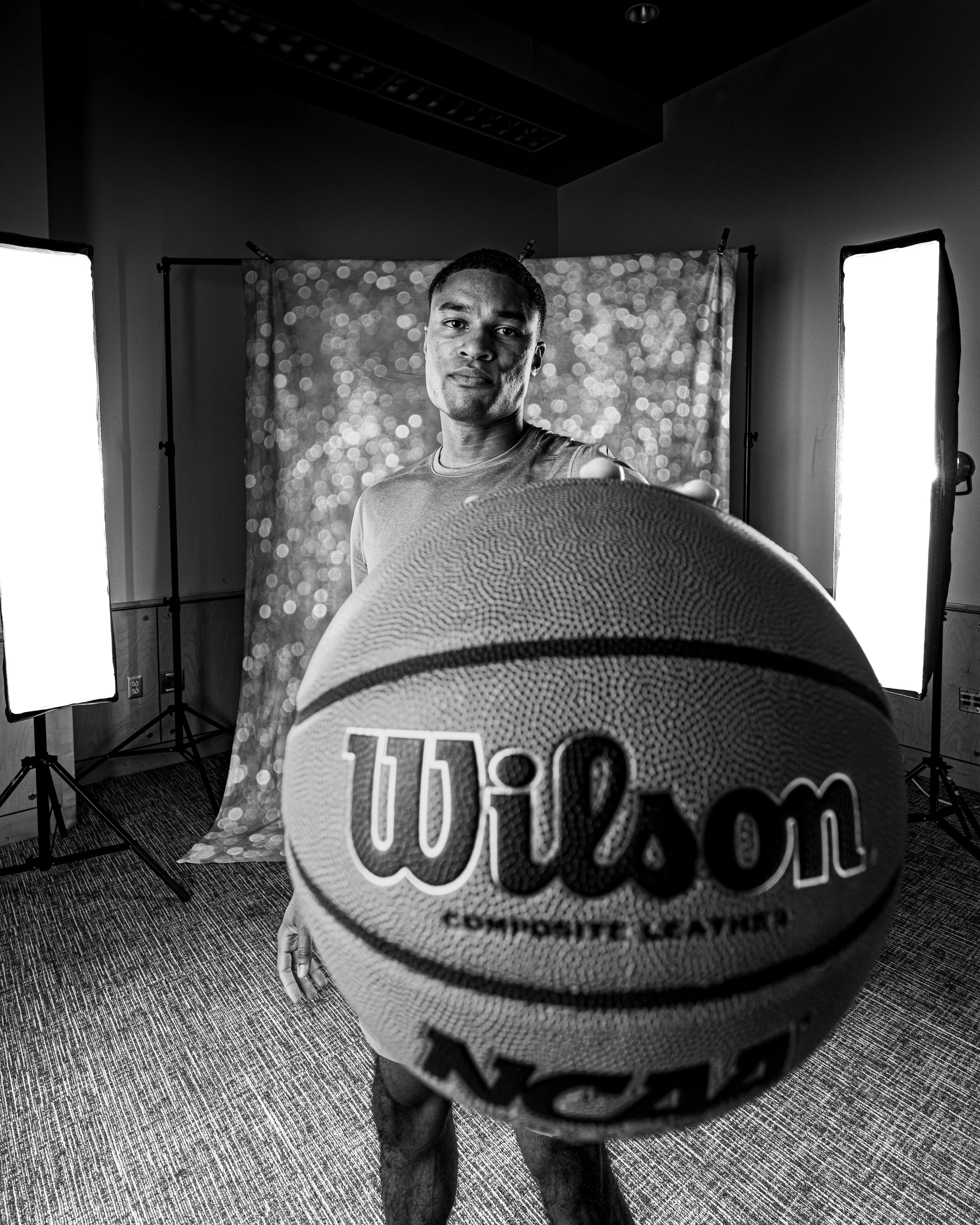 Black and white portait of a man palming a basketball looking into the lens. Portait taken by an Austin Texas Photographer in Austin Texas.