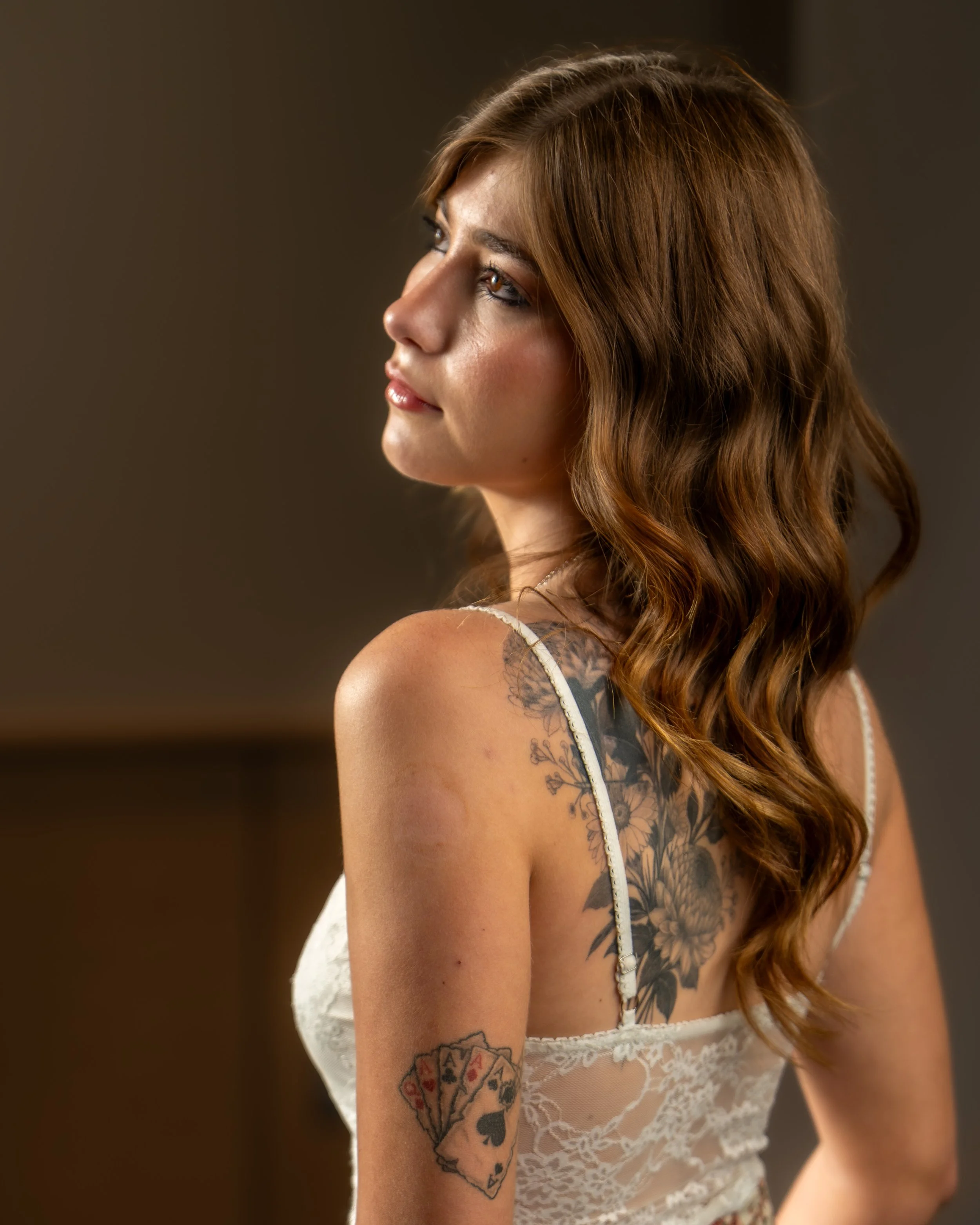 A portrait of a woman with her back to the camara revealing several tattoos and light bouncing off her eyes. Photo taken in Austin Texas by Austin Photographer.