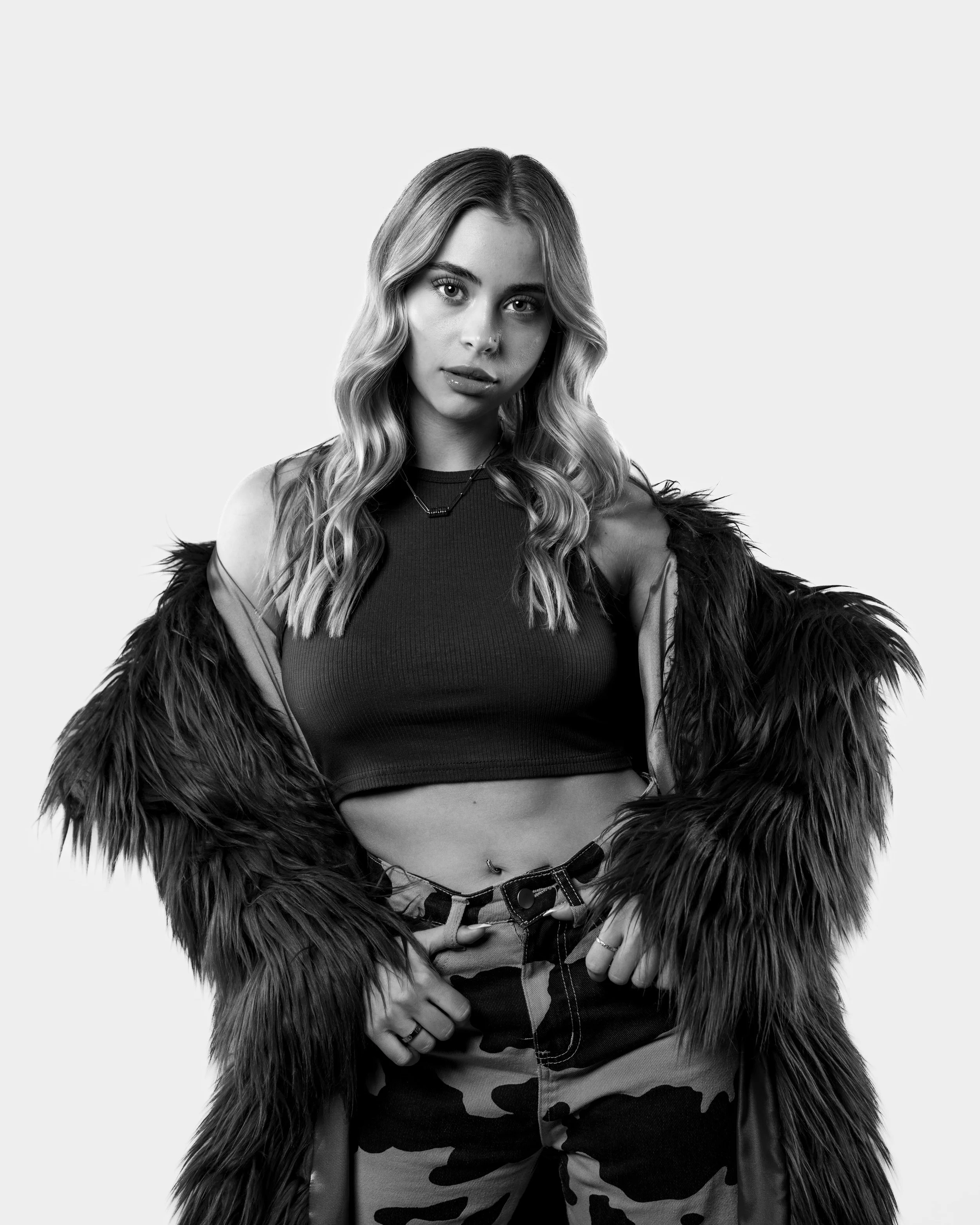 Black and white portait of woman wearing a fur coat and cow print pants staring into the camera. Photo taken in Austin Texas by Austin Texas photographer.