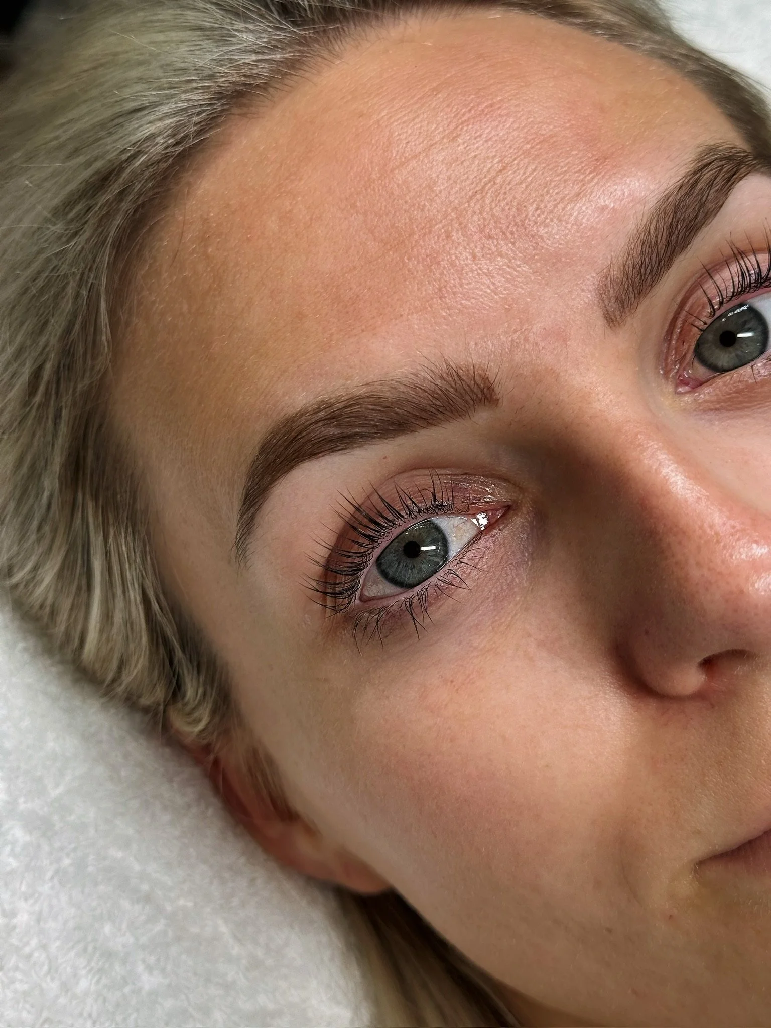 Close-up of a woman's face highlighting her beautifully shaped eyebrows, eye makeup, and clear skin.