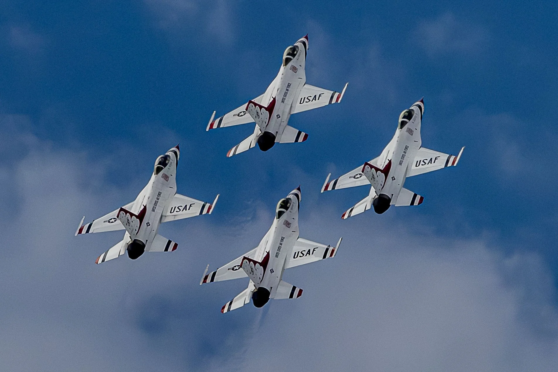 Four USAF fighter jets flying in formation against a cloudy sky.