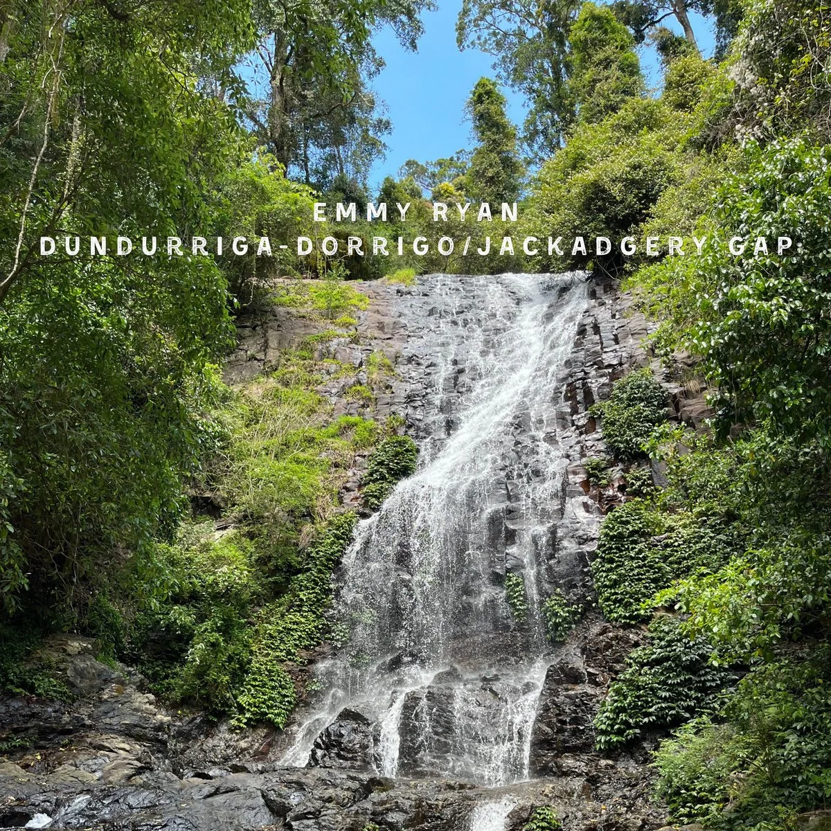 Waterfall flowing down a rocky cliff surrounded by lush green trees.