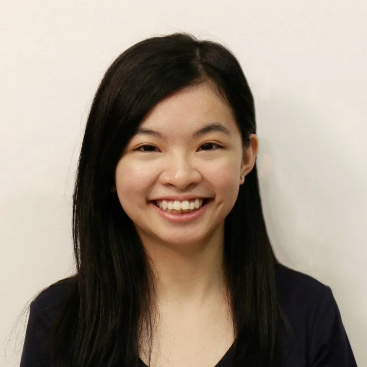 A young woman with long black hair, smiling in front of a plain white background.