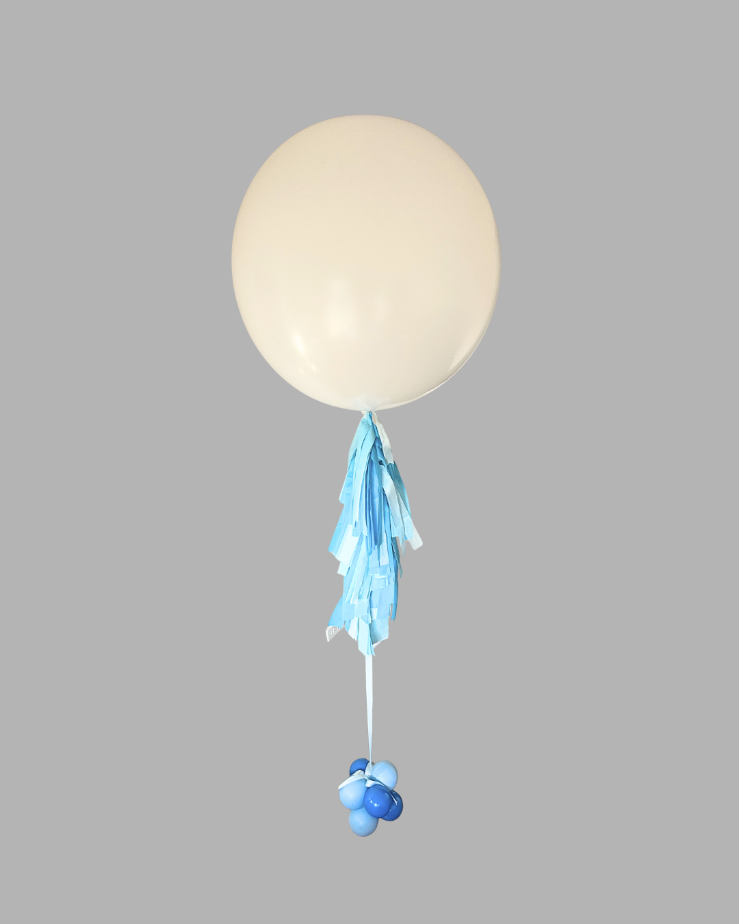 White helium balloon with blue fringe streamers and a cluster of blue and light blue balloons at the base on a gray background.