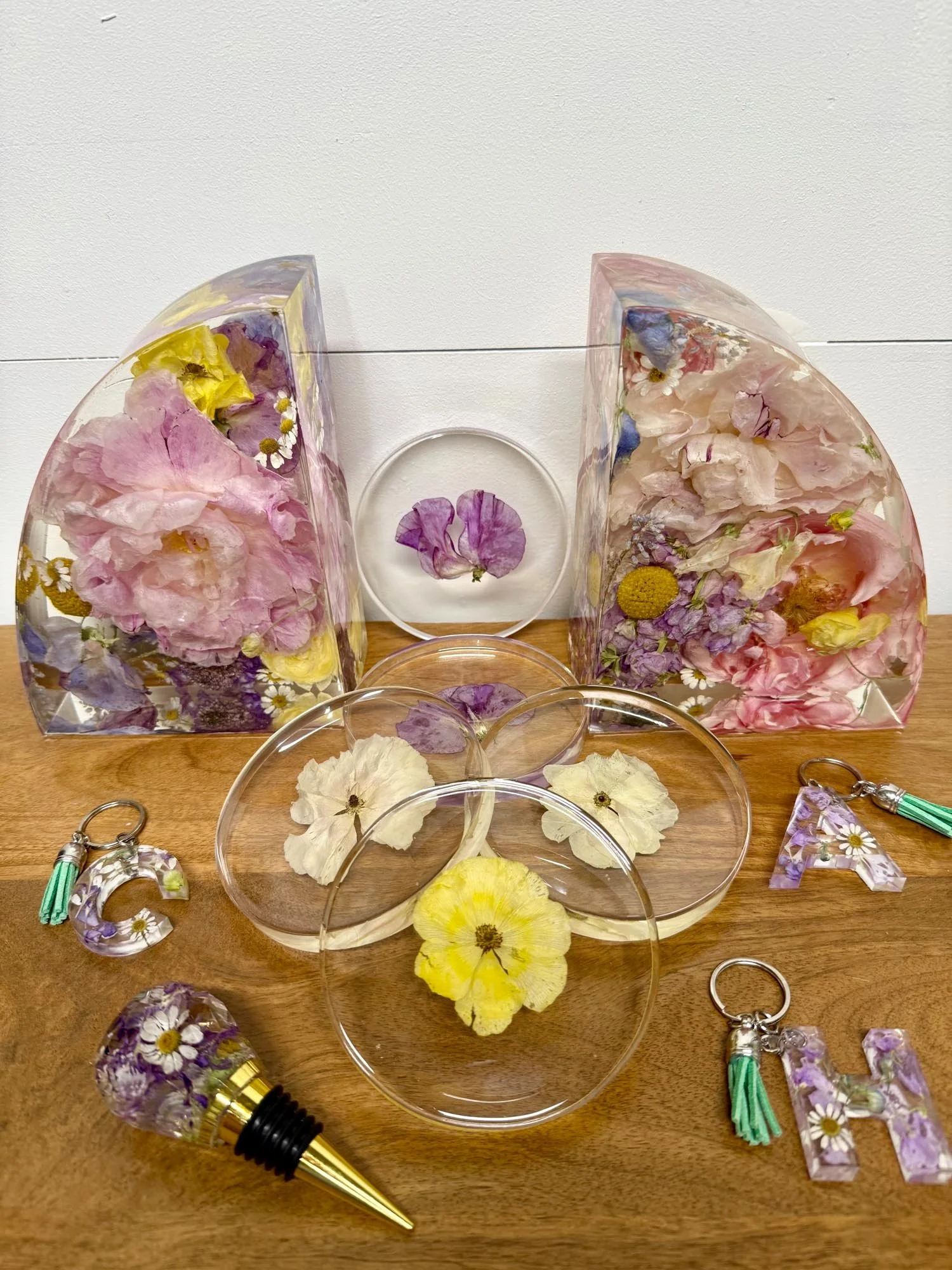 Collection of resin bookends, coasters, wine toppers, and keychains preserving wedding flowers, made by Beaux’s Botanical Preservation in the Outer Banks