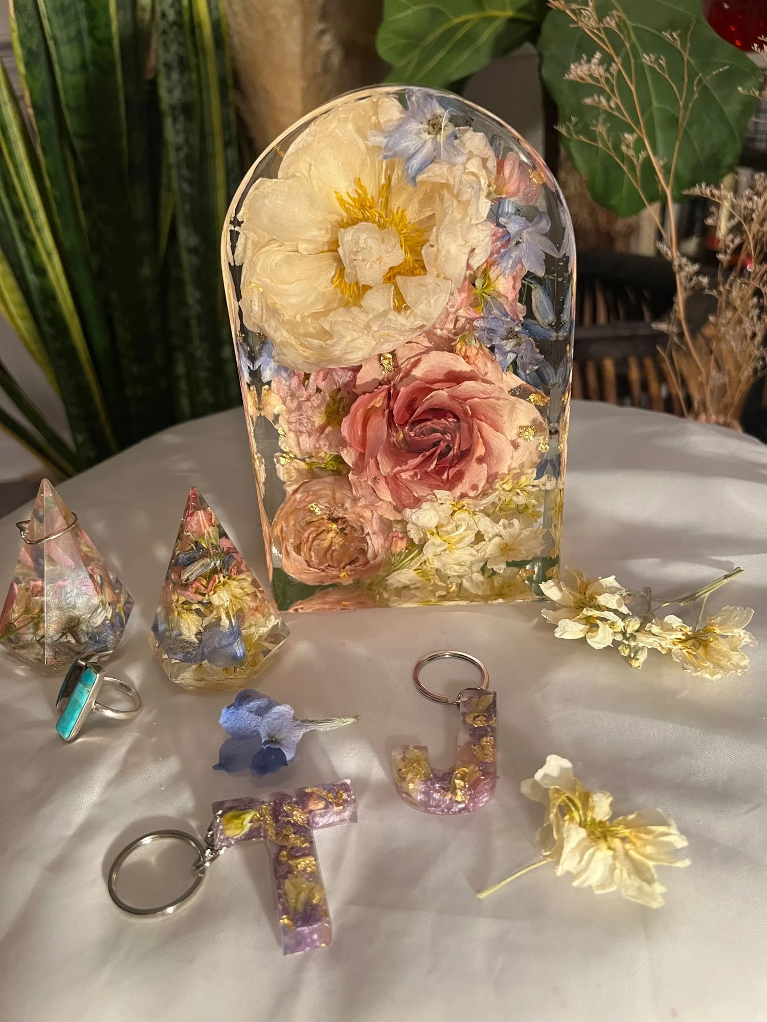 Collection of preserved flower keepsakes including an arch block, keychains, and ring displays, handcrafted by Beaux’s Botanical Preservation in Outer Banks NC