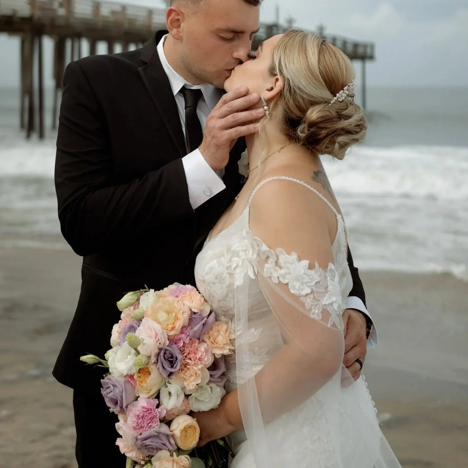 Wedding couple kissing on an Outer Banks beach while holding their bouquet, later preserved by Beaux’s Botanical Preservation in Outer Banks NC
